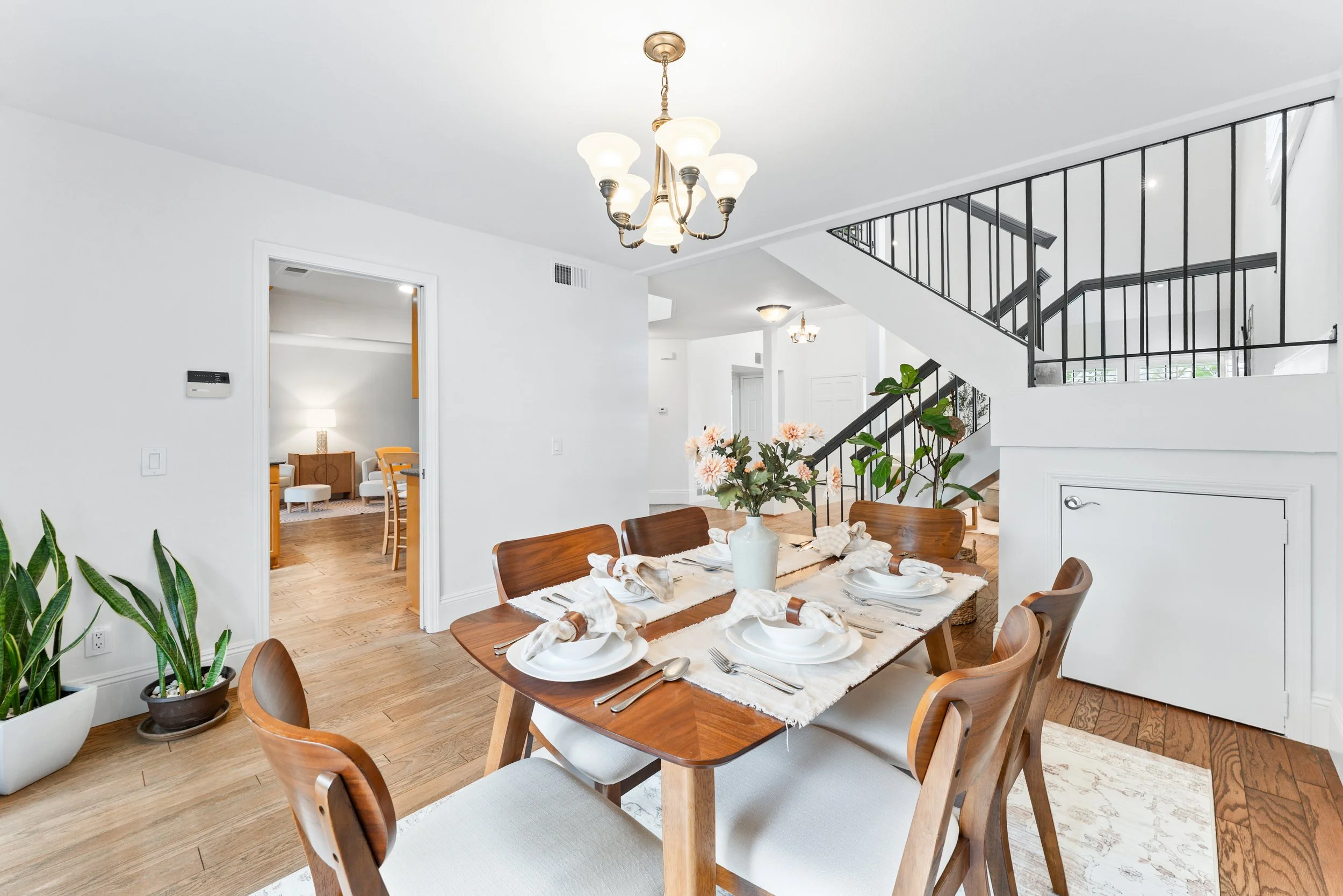 selling a woodbridge irvine home - wooden dining room table with wooden chairs, white walls, and a staircase wrapping around