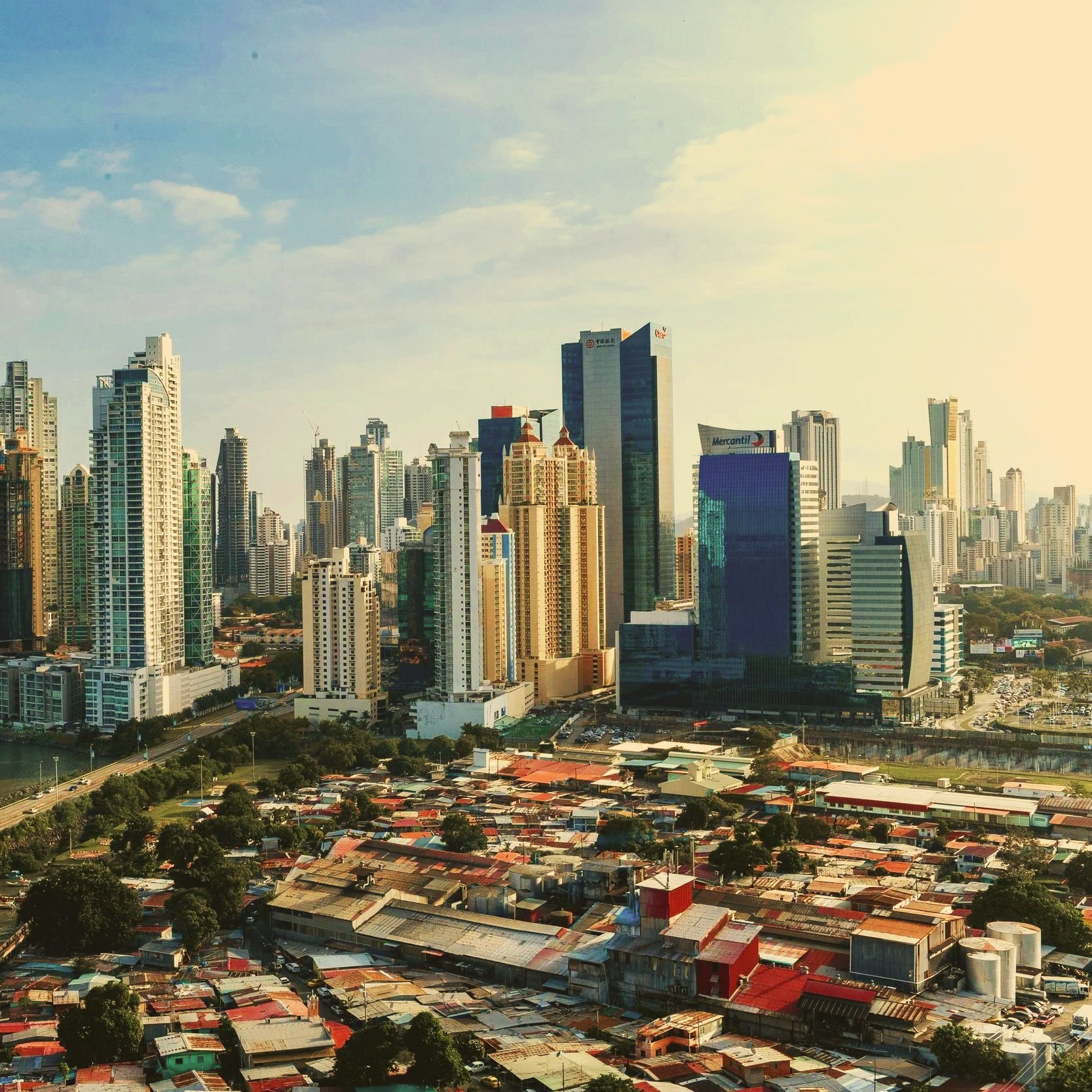 Vista de una ciudad moderna con rascacielos y un barrio de casas pequeñas en primer plano.