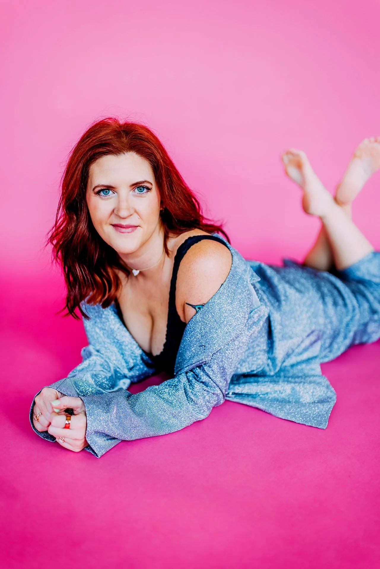 Portrait of The Sex Copywriter, Athena Gayle on her elbows on the floor looking suggestively at the camera