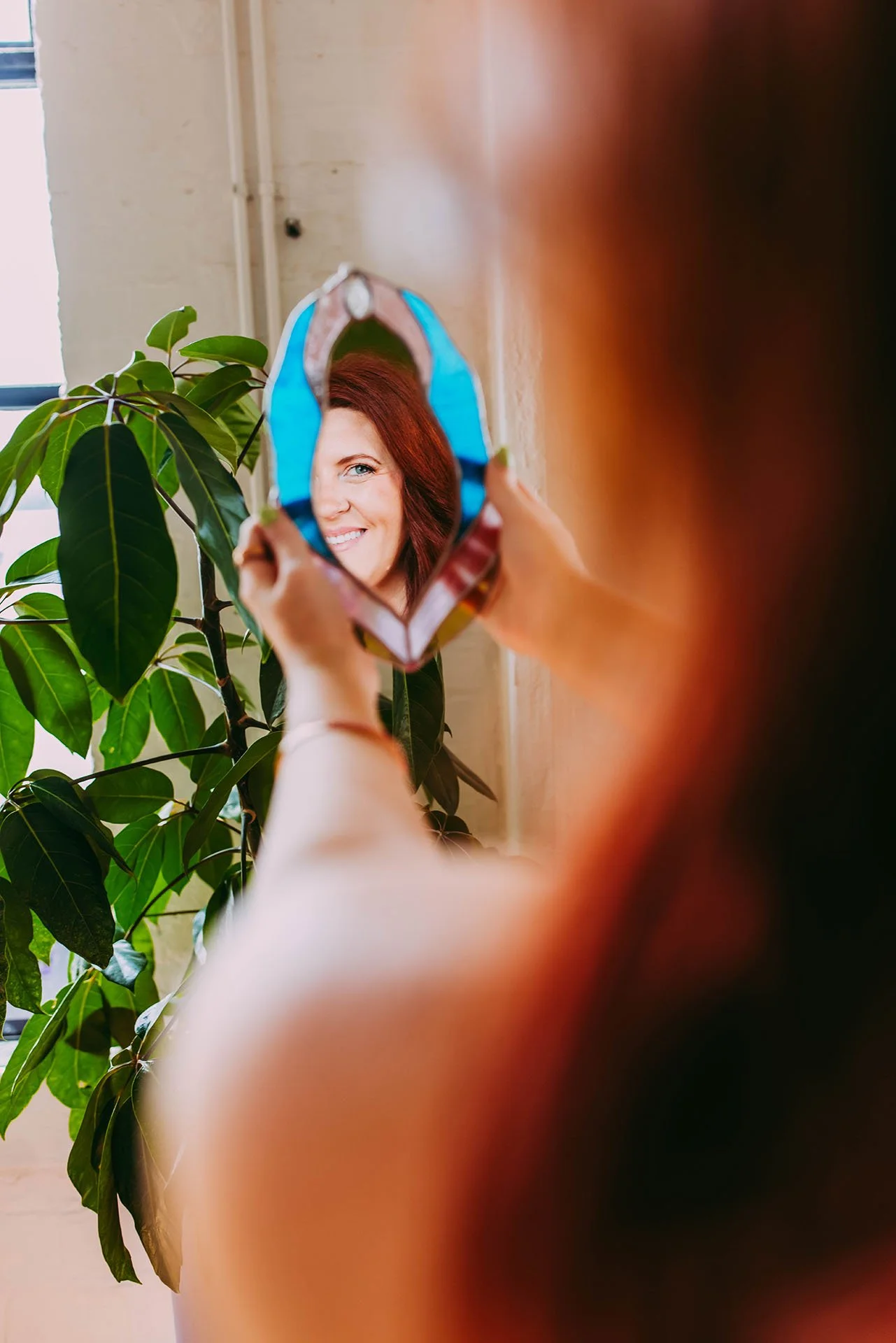 Image of The Sex Copywriter, Athena Gayle's reflection looking into a vulva shaped mirror