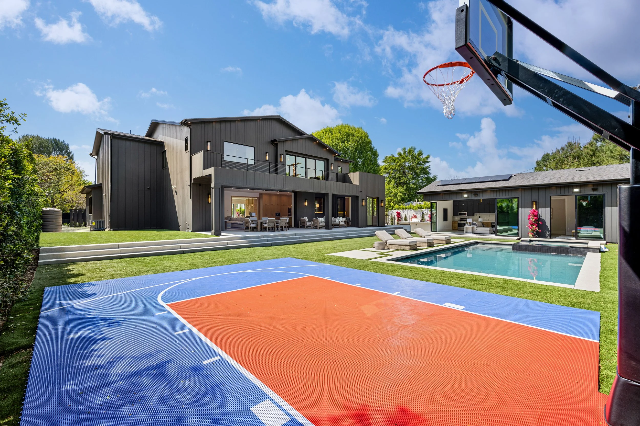 Luxury outdoor basketball court beside a modern pool, showcasing the large-scale amenities and recreational spaces our team manages and maintains for high-end estates.