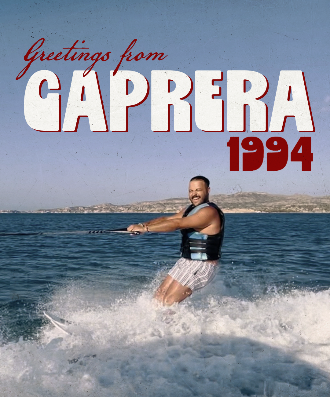 Person wakeboarding on water with a shoreline in the background, wearing a life vest and striped shorts, smiling. Text overlay says 'Greetings from Caprera 1994'.