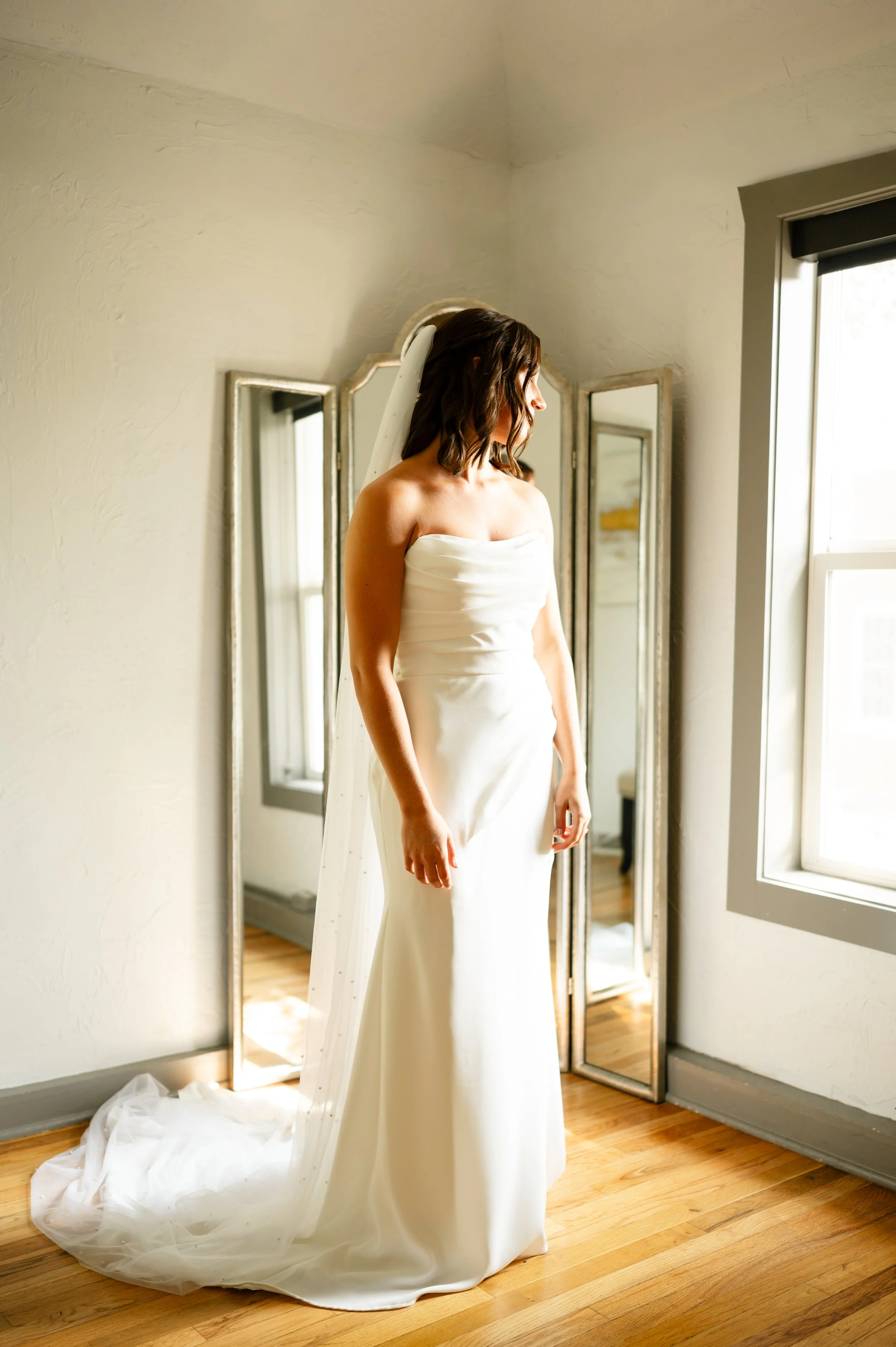 Bride getting ready with strapless dress and cathedral pearl veil before first look with dad on wedding day at the Mill in Windsor Colorado