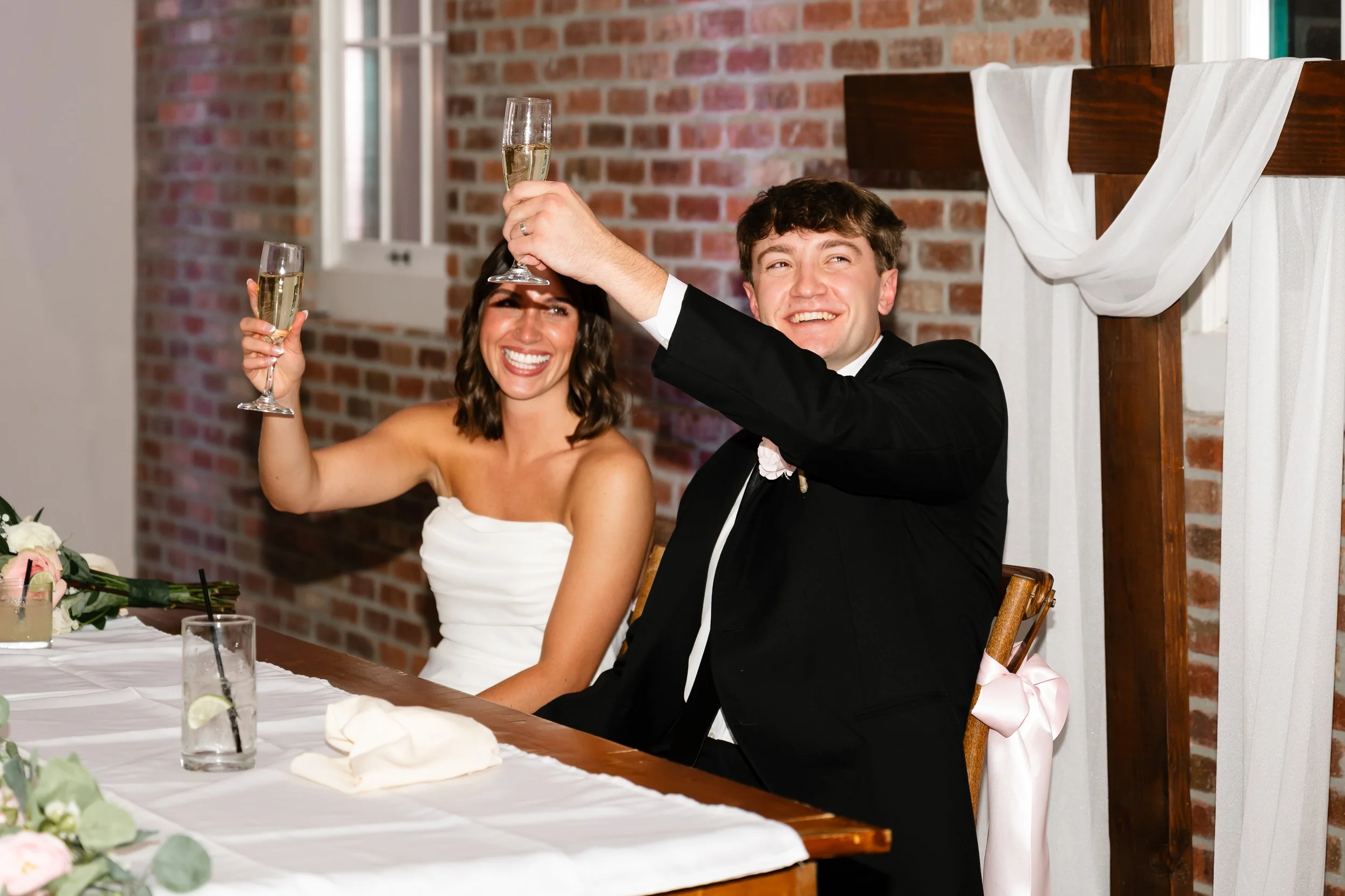 A married couple celebrating after their wedding ceremony by toasting during their best man's speech inside the reception space at The Mill in Windsor Colorado