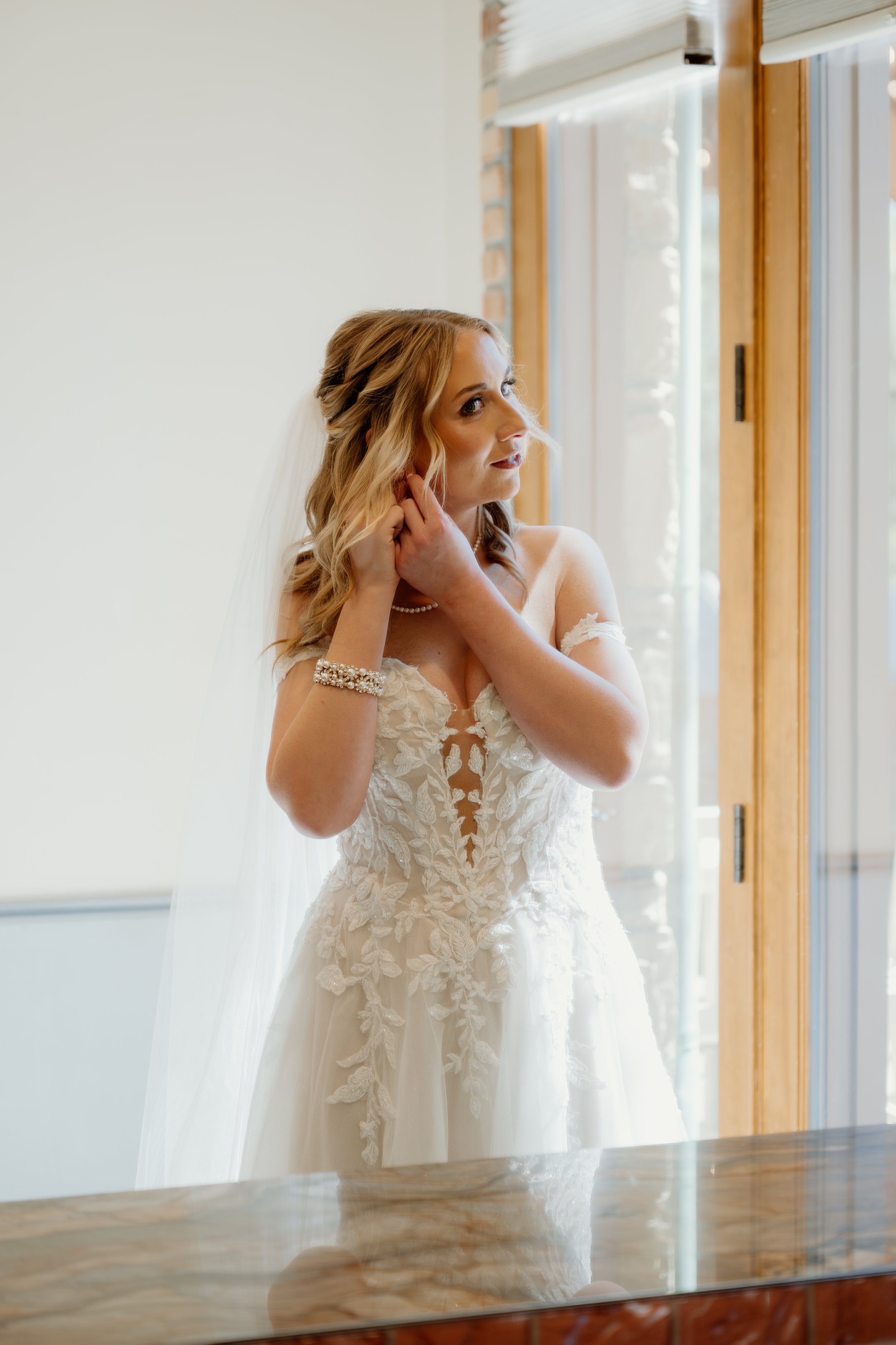 Bride getting ready putting in earrings before first look on wedding day at Della Terra in Estes Park Colorado