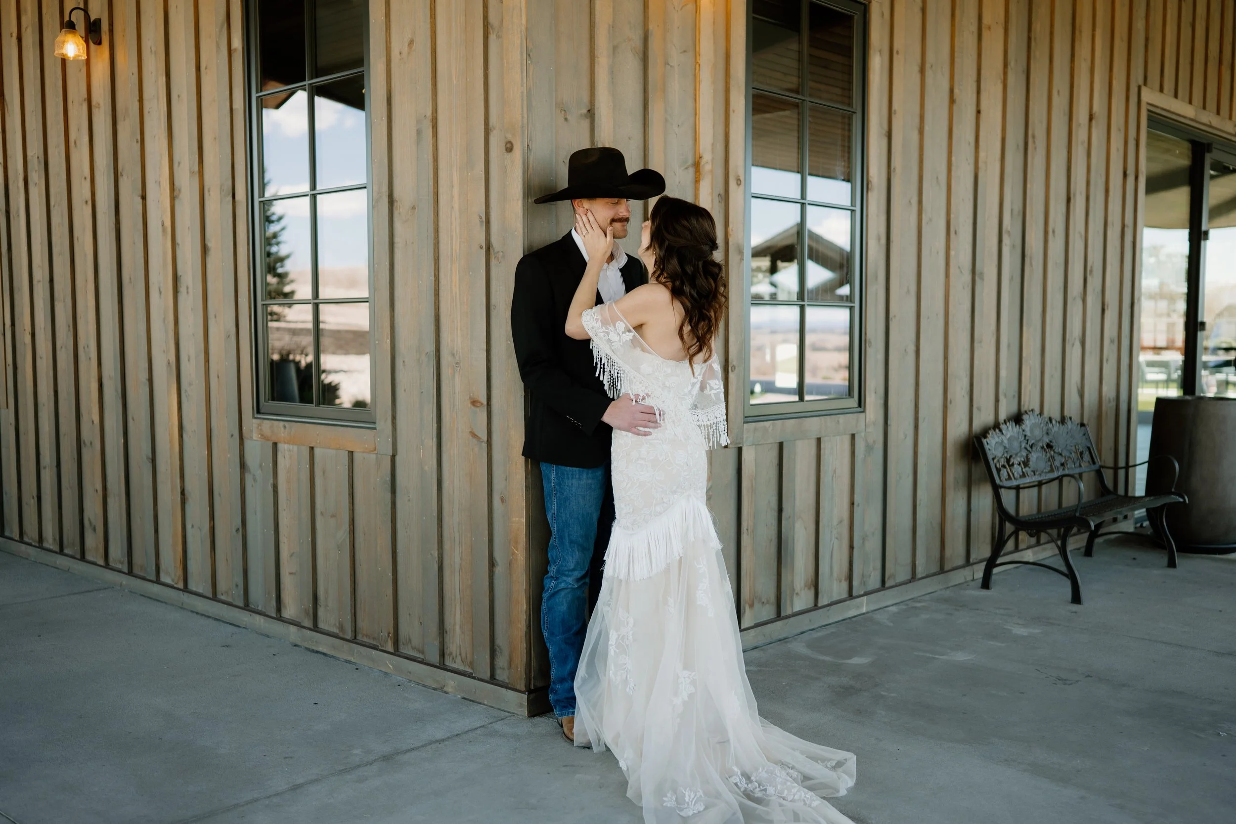 Married western couple holding each other after their wedding wearing a vintage wedding dress and a cowboy hat near Denver Colorado