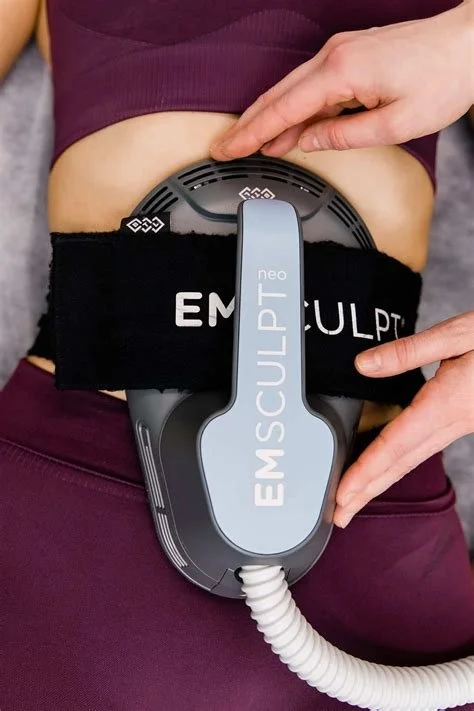 Person using EMSculpt Neo abdominal treatment device with hands adjusting the device on their waist.