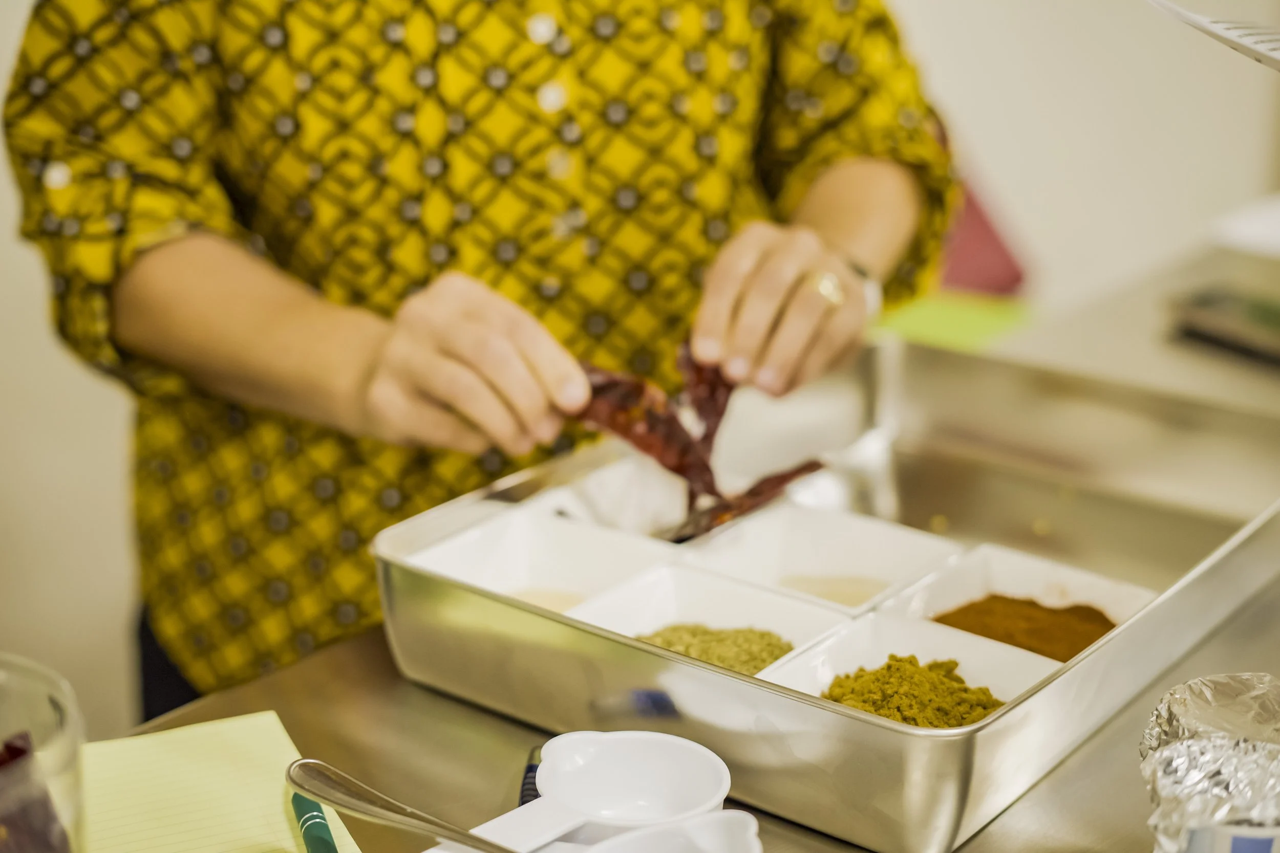 Person handling dried herbs or spices in a kitchen or food preparation area.