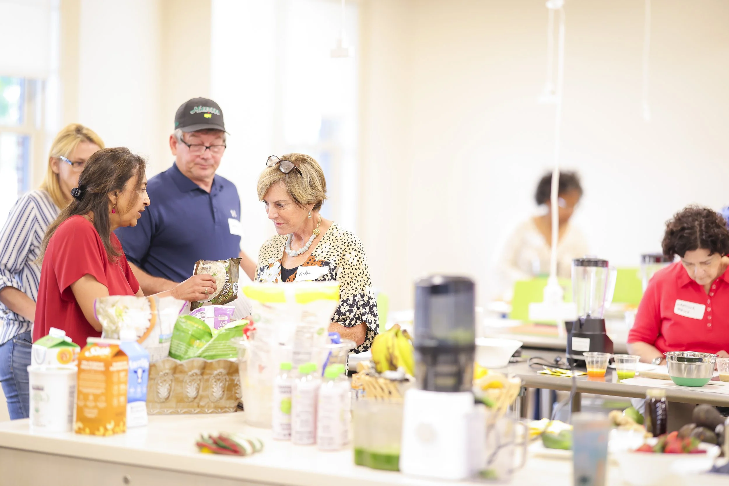 People in a kitchen or cooking class preparing food, with ingredients and appliances on the counter.