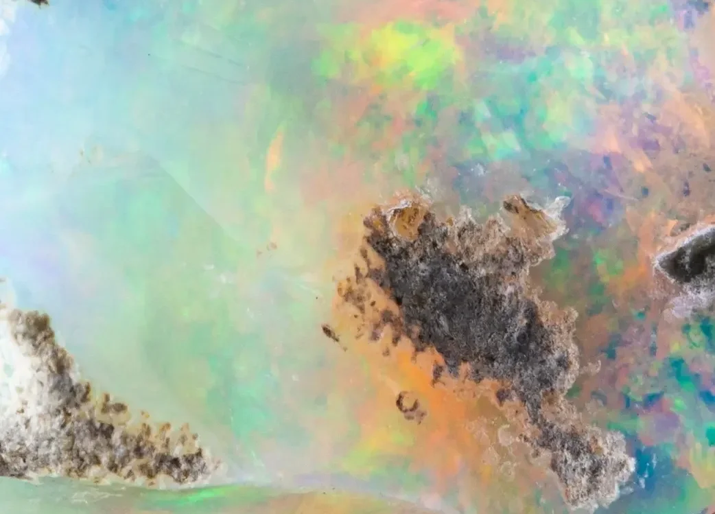 Close-up of a multicoloured, iridescent opal stone. Centred Wellness therapist.
