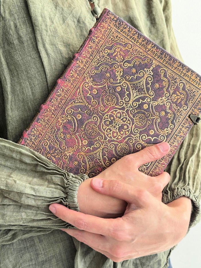 Counsellor and psychotherapist holding a vintage, ornate book with intricate gold cover design.