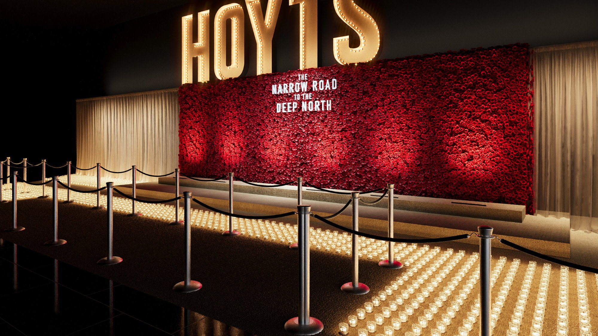 A large illuminated sign that reads 'HOLLYS' above a wall of red roses with a sign that says 'The Narrow Road to the Deep North'. The area is decorated with small candles on the ground, and there is a rope barrier in front for visitors.