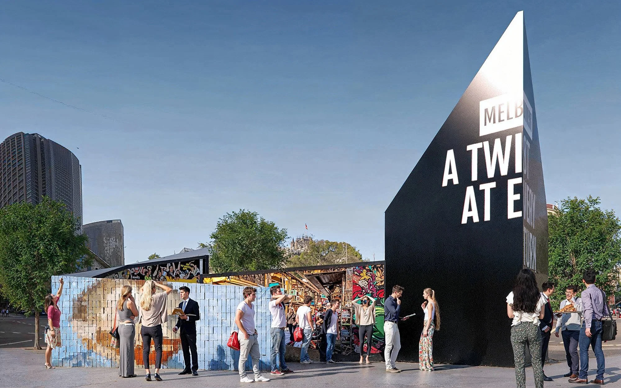 A group of people standing in line outdoors in front of a large black structure with white text.