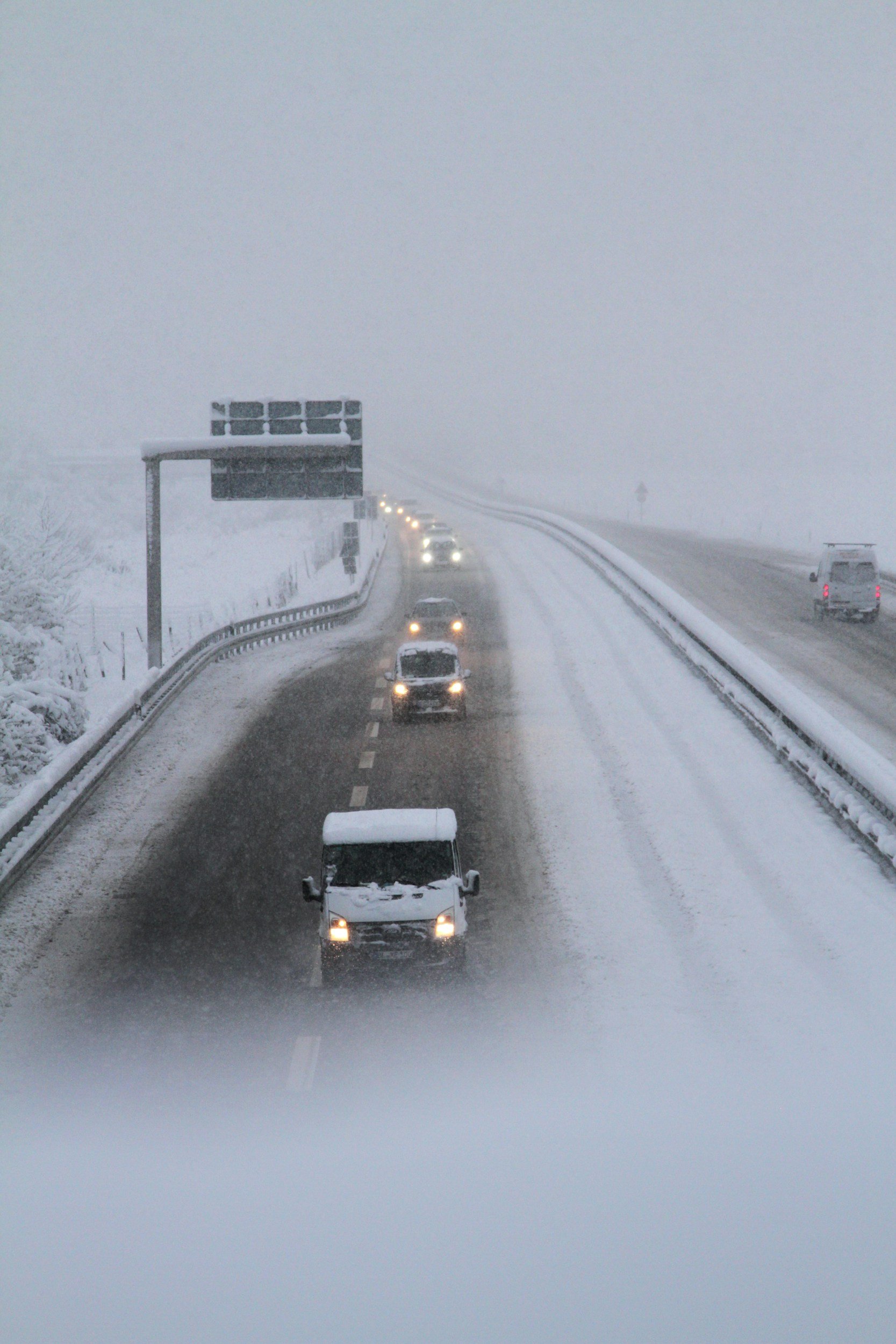Cars and trucks driving on a snowy, foggy interstate highway
