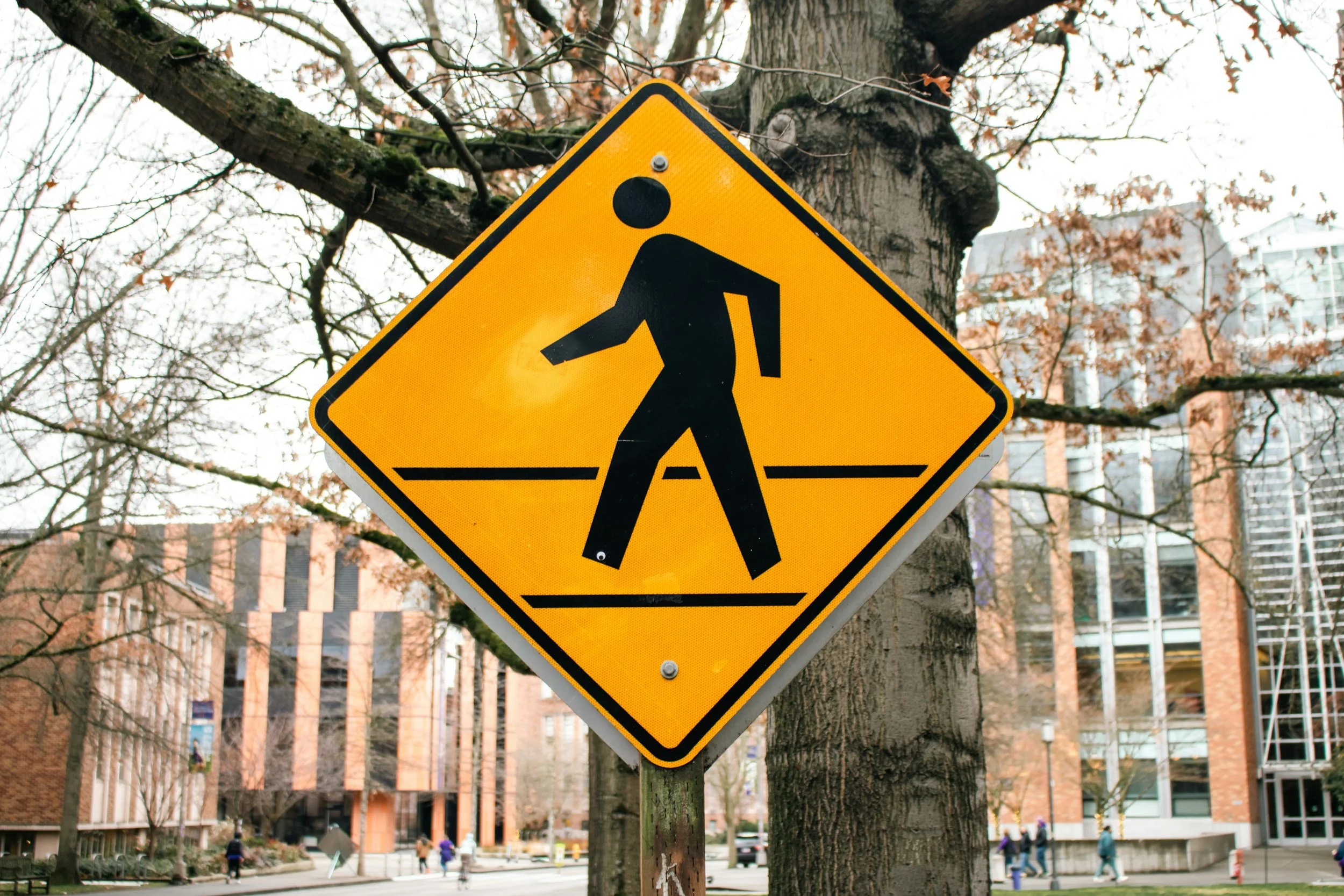 Yellow pedestrian crossing sign near brick buildings