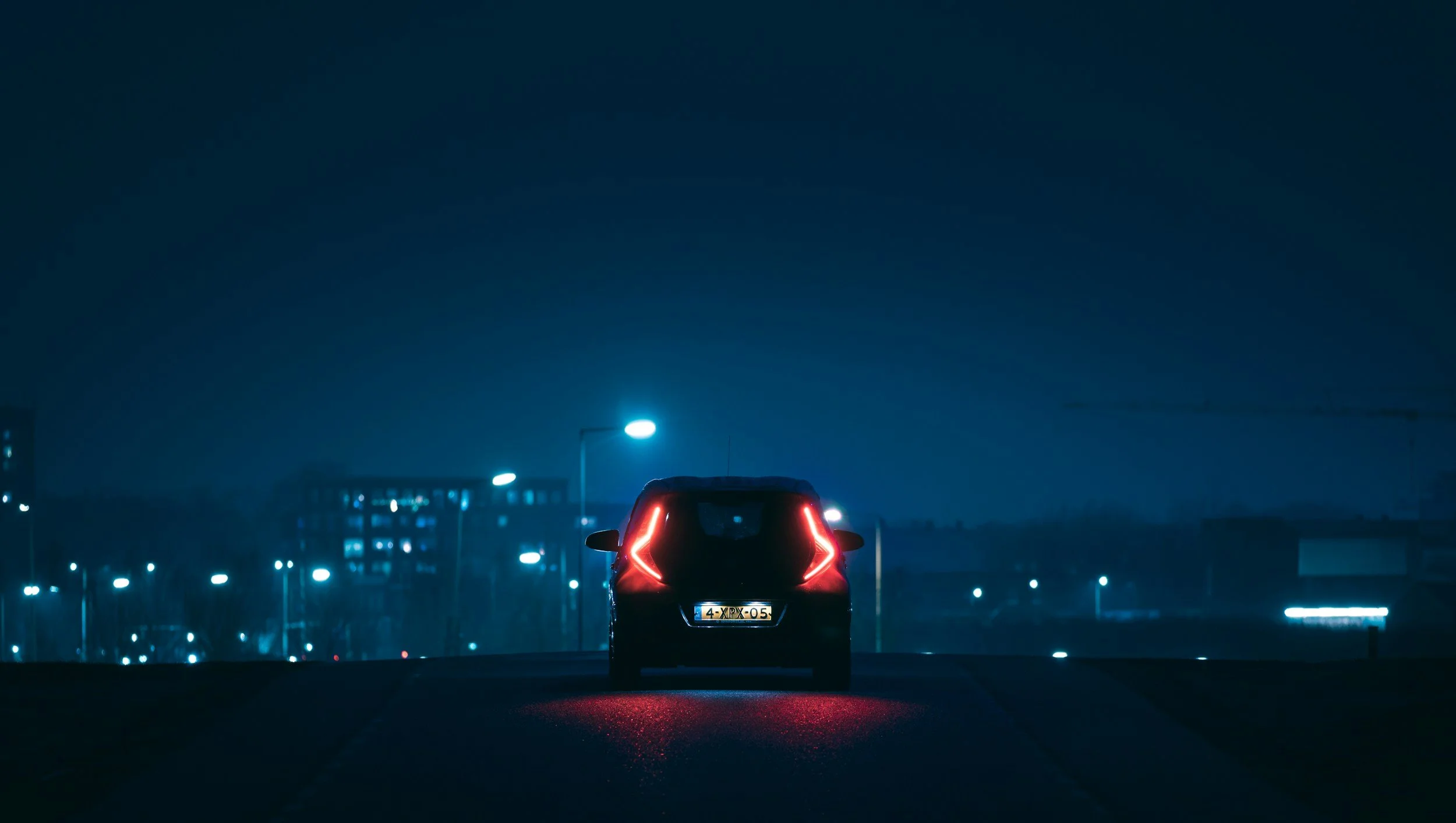 Car with taillights glowing on a city street at night
