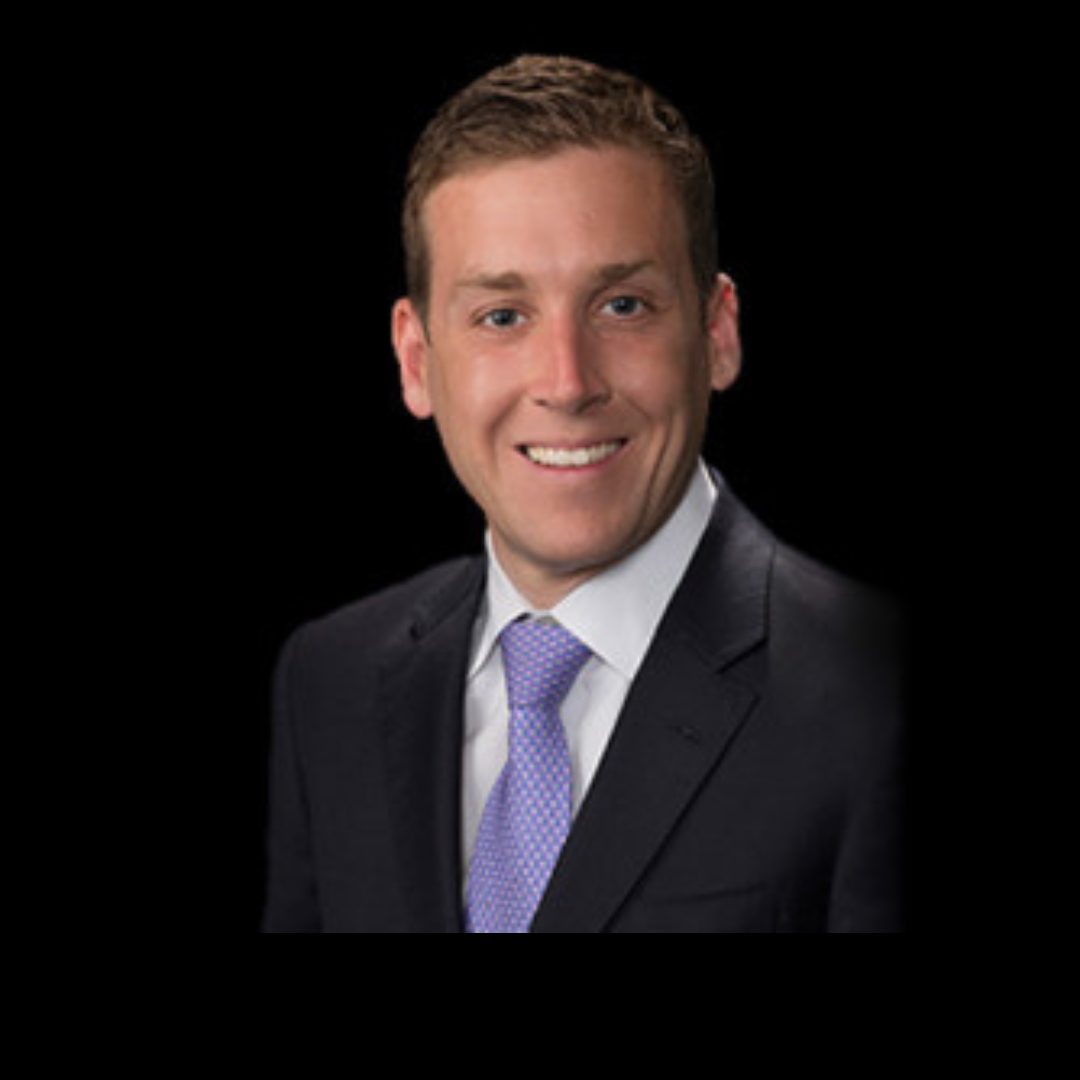 Professional headshot of a smiling man in a suit and tie against a black background.