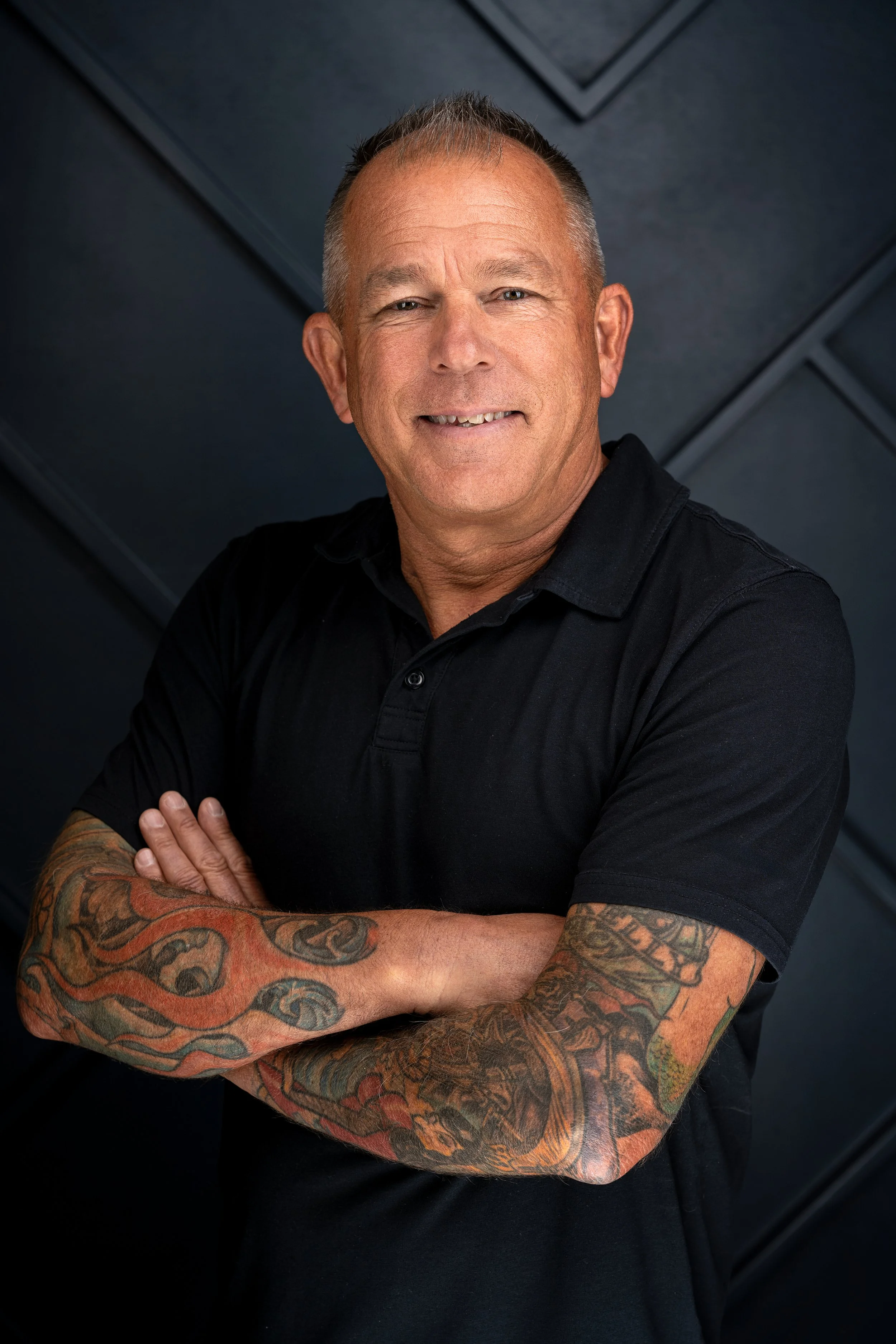 Portrait of a Sacramento CA Tankersley Build Co Employee headshot. He is standing against a dark, textured background.