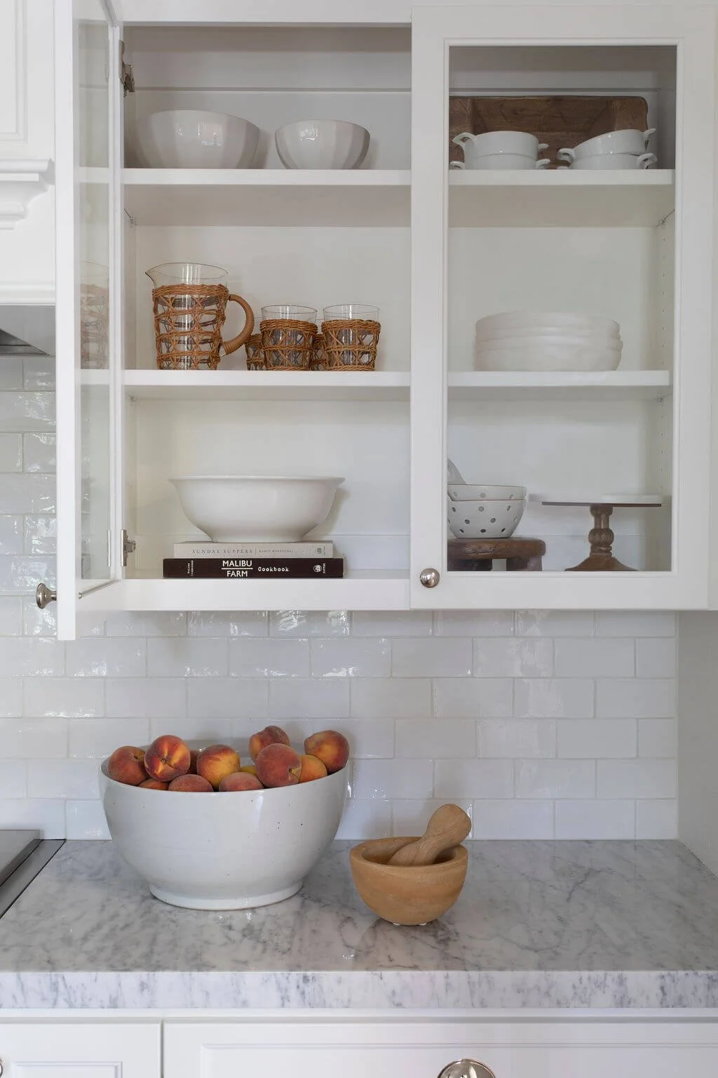 Glass front cabinets display bowls, cups, and cookbooks