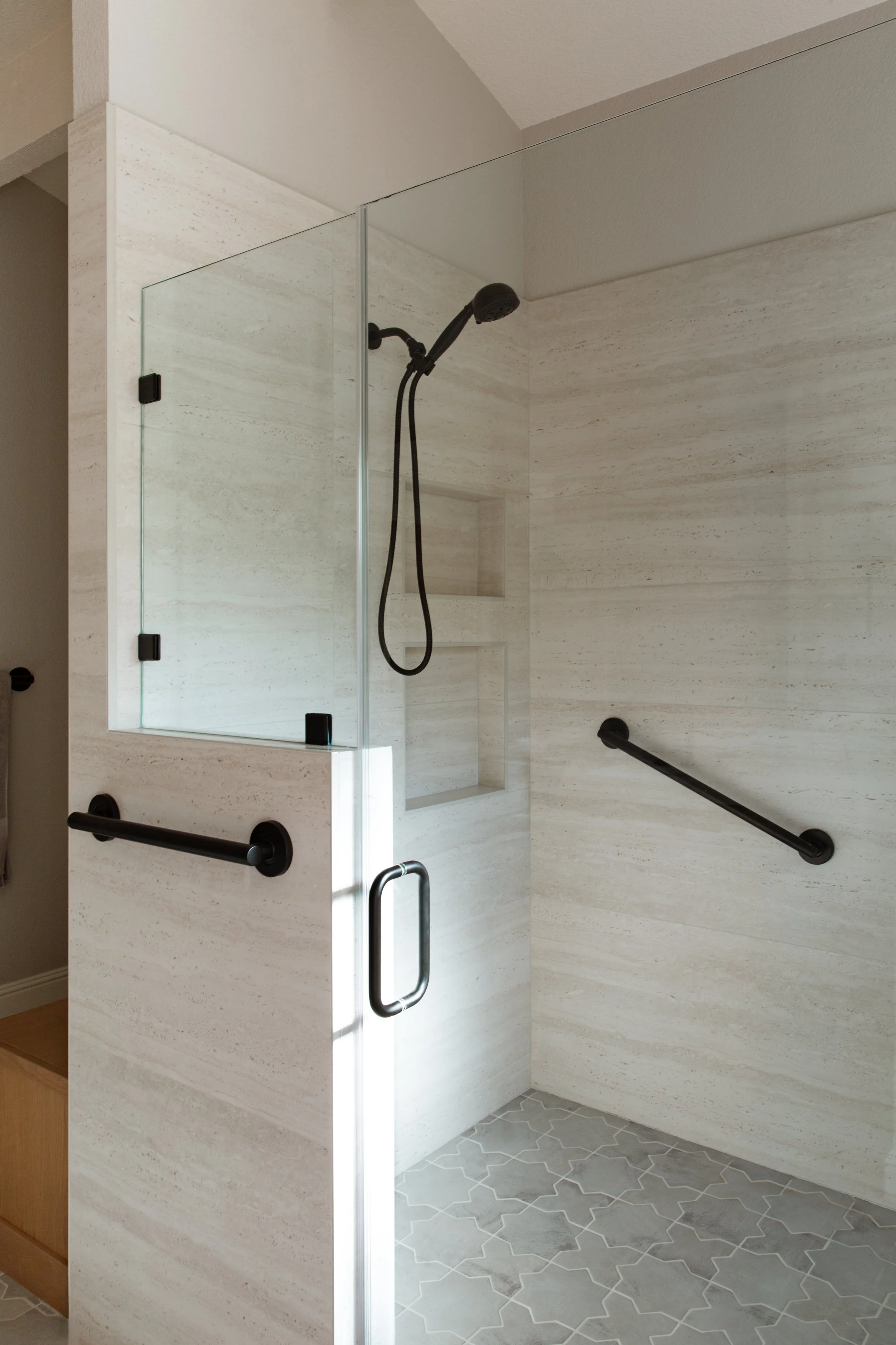 Walk-in shower with modern, black grab bars and a handheld shower feature in folsom aging-in-place remodel