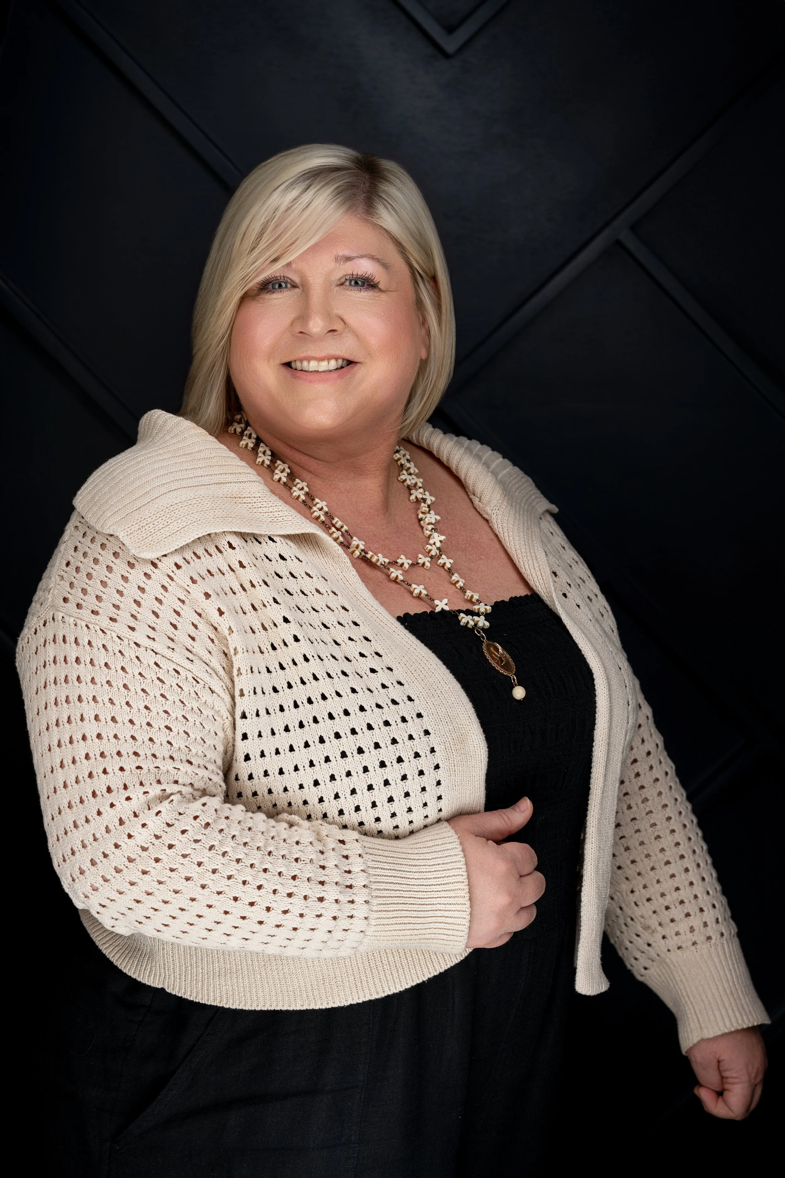A smiling Tankersley Build Co Employee headshot. She is standing against a dark, textured background.