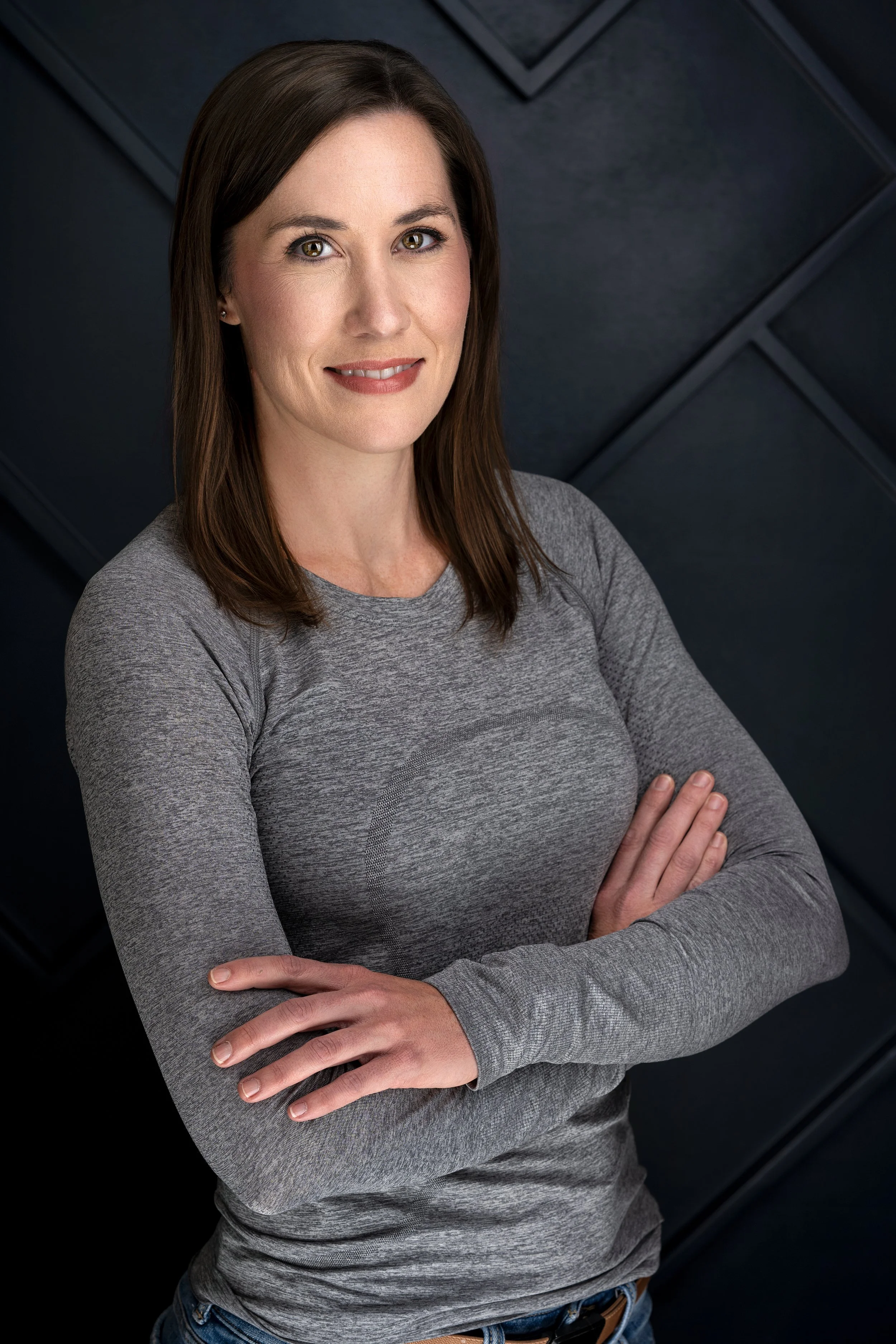 A smiling Tankersley Build Co Employee headshot. She is standing against a dark, textured background.
