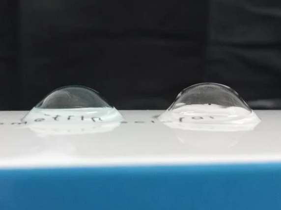 Close-up of two silicone gel contact lenses on a white and blue surface.