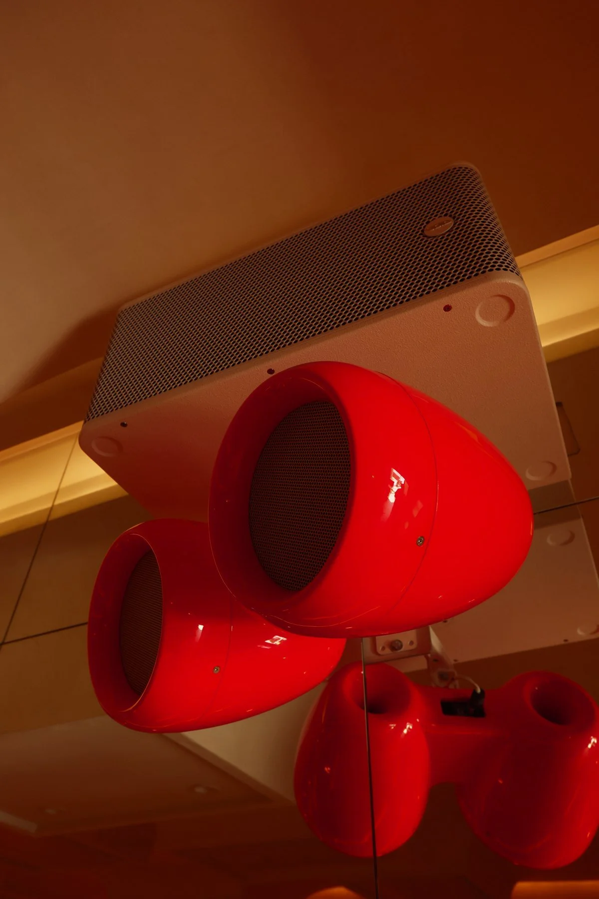 A close up of the red VOID Acoustics speakers hanging from the ceiling