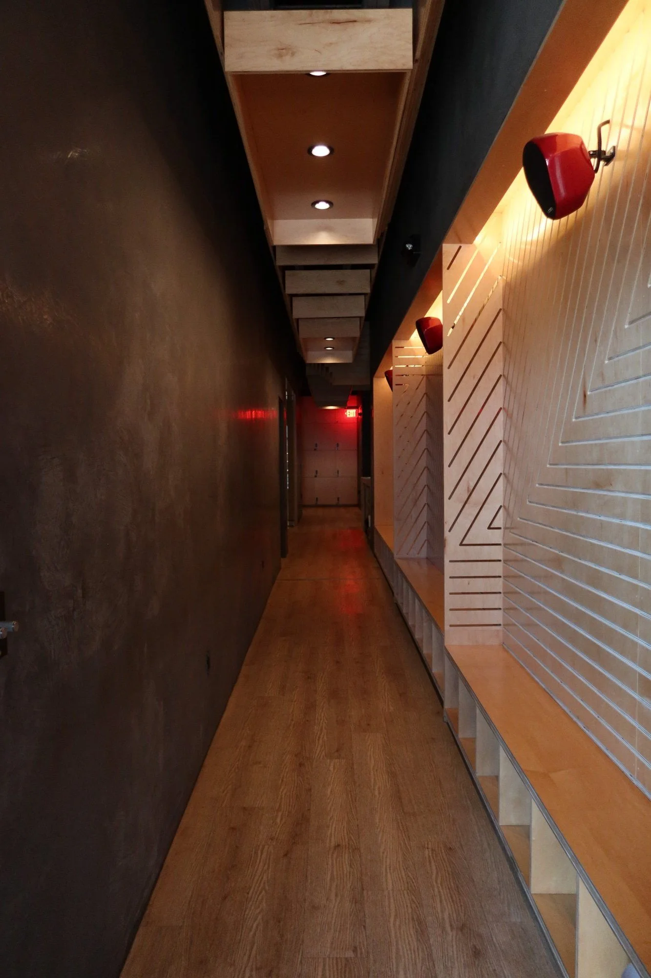 The West Hollywood hallway: slatted wood wall, red VOID speakers & a long warm floor