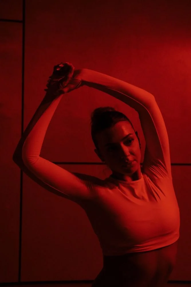 Arms overhead, stretching against a red wall
