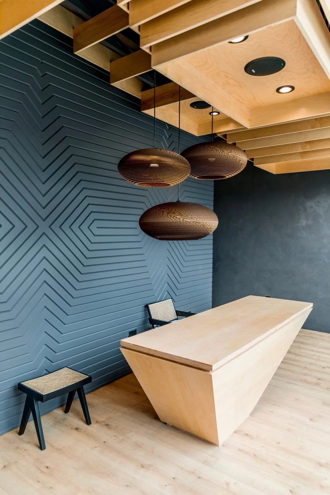 The West Hollywood front desk under woven pendant lights & a carved charcoal wall