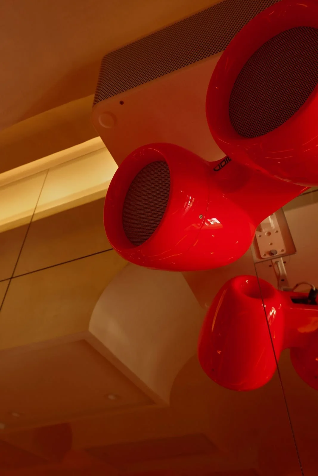 Red VOID Acoustics speakers suspended from the curved ceiling