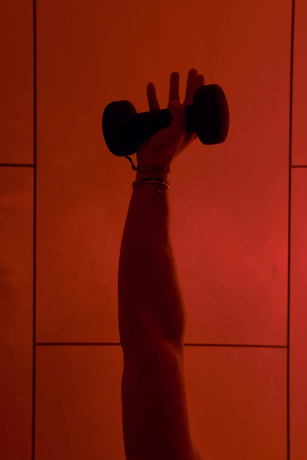Power Pilates: a hand gripping a dumbbell overhead against a red wall