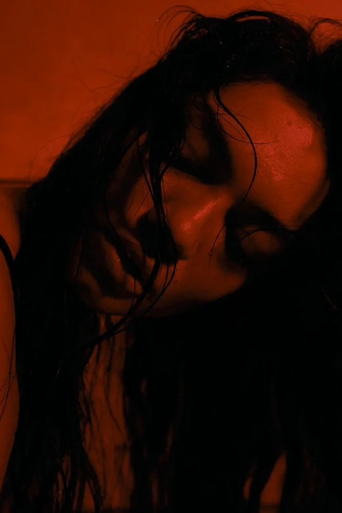 Portrait in red light, damp hair across the face