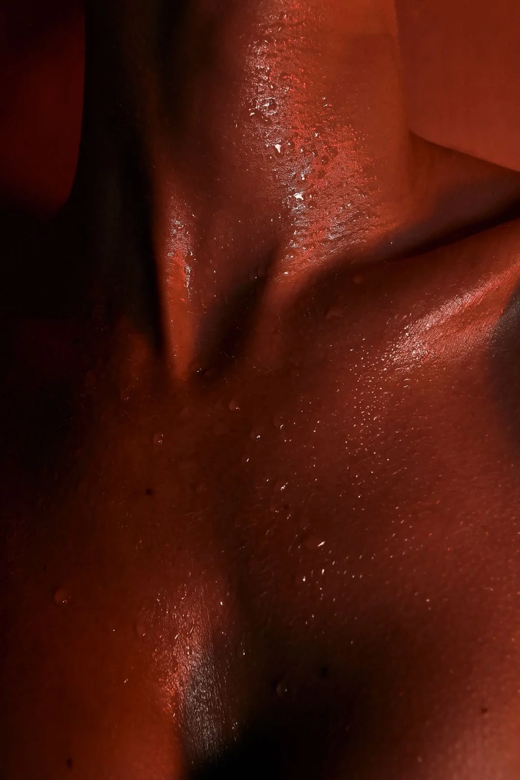 Close-up of sweat on a collarbone in warm red light