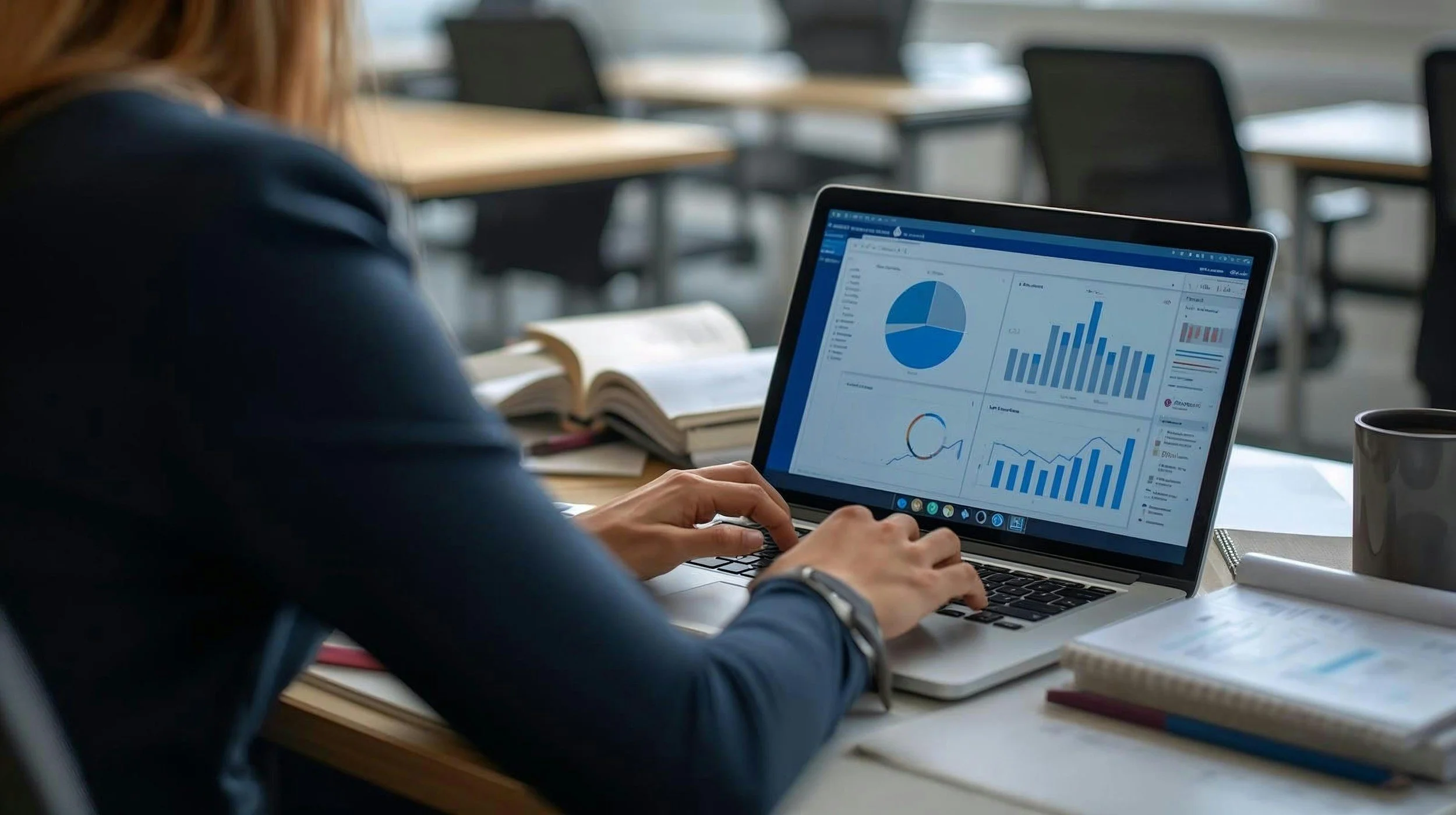 Person working on a laptop displaying financial graphs and charts in a conference room.