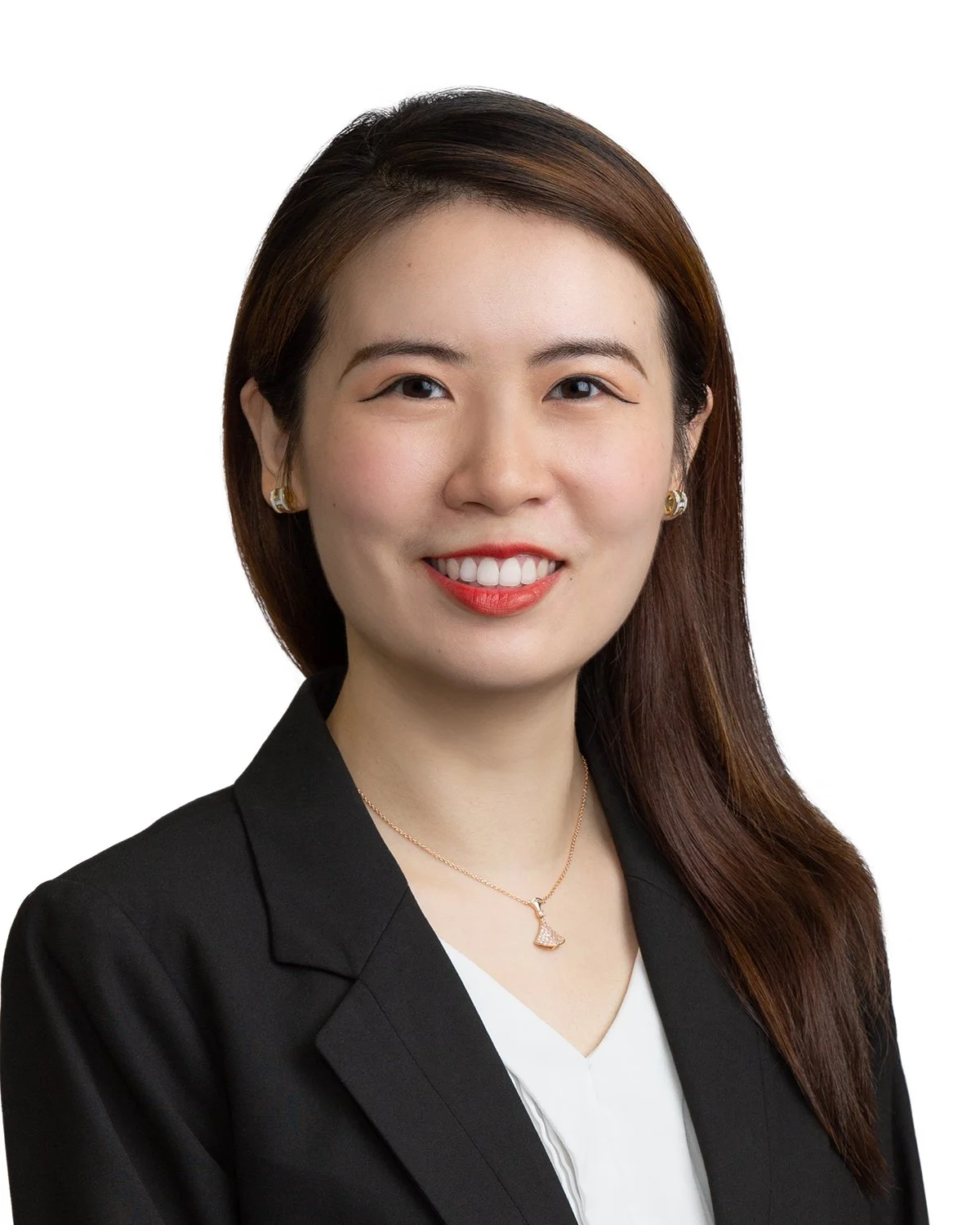 A professional woman with shoulder-length brown hair, smiling, wearing a black blazer, white top, and a gold necklace with a sailboat pendant, against a white background.
