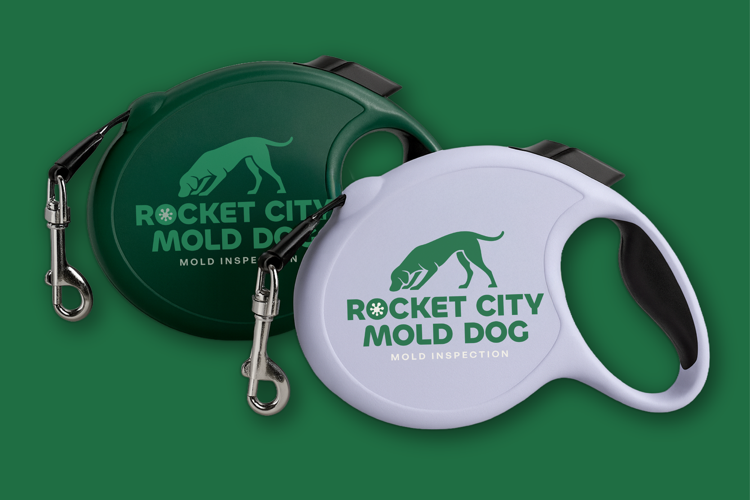 Two retractable dog leashes, one green and one white, with black handles and metal hooks, displaying the logo and text for Rocket City Mold Dog against a green background.