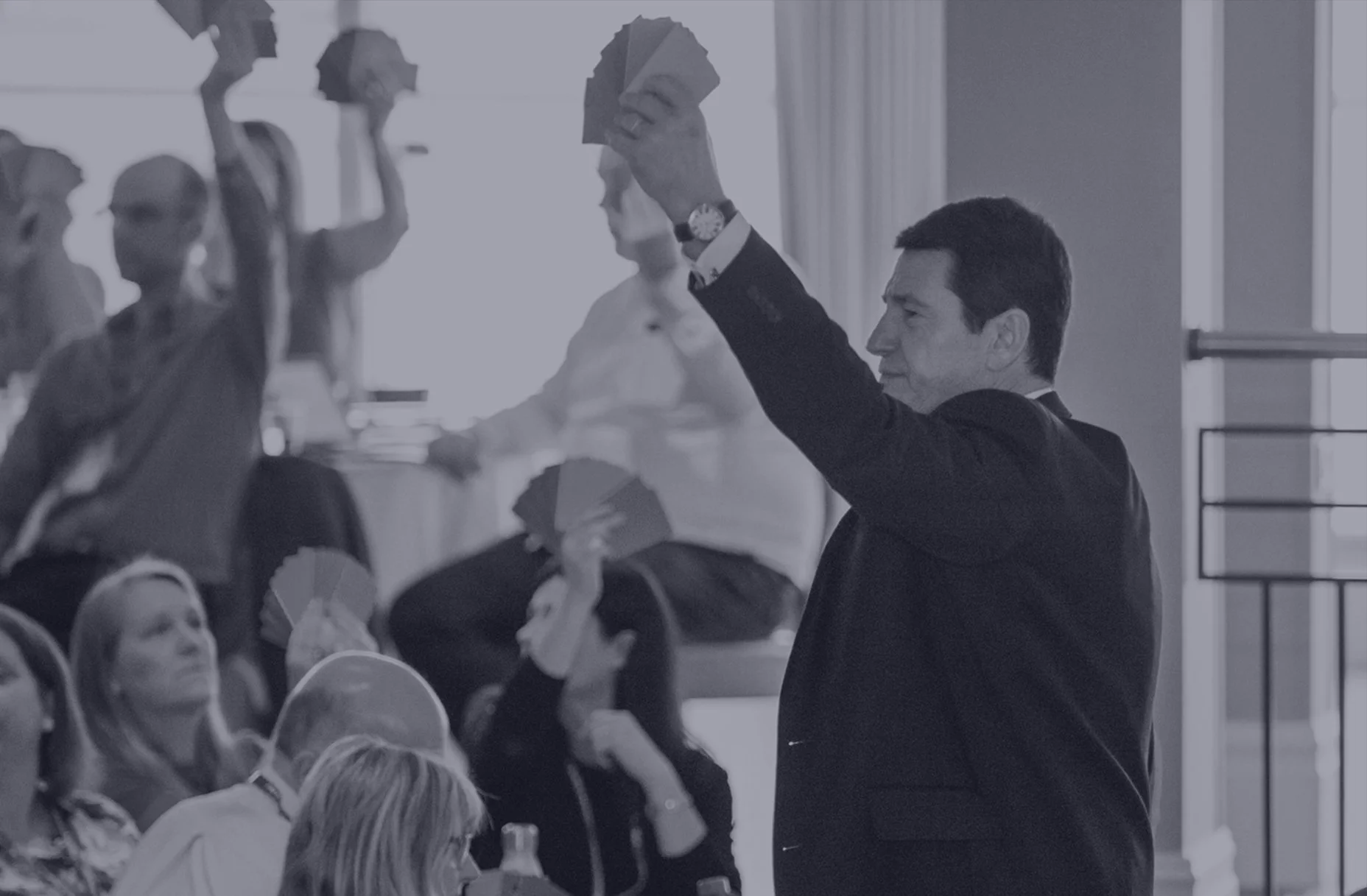 Nick Saunders in a dark suit holding up a fan of Discovery Insight Profiling cards at a conference event.
