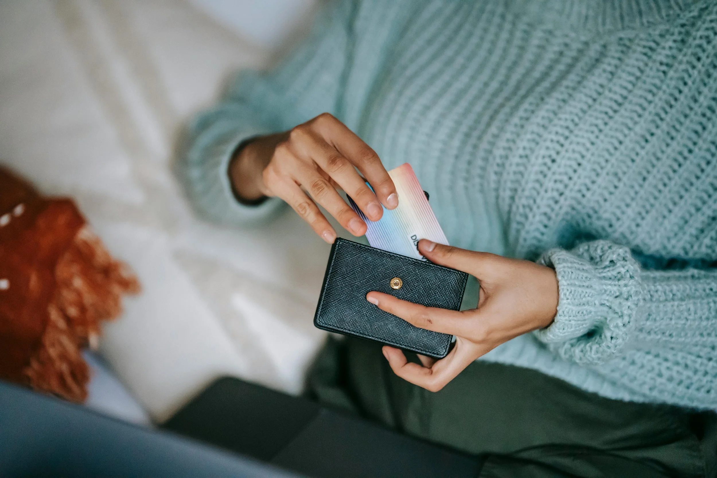 Person removing a credit card from a black wallet.
