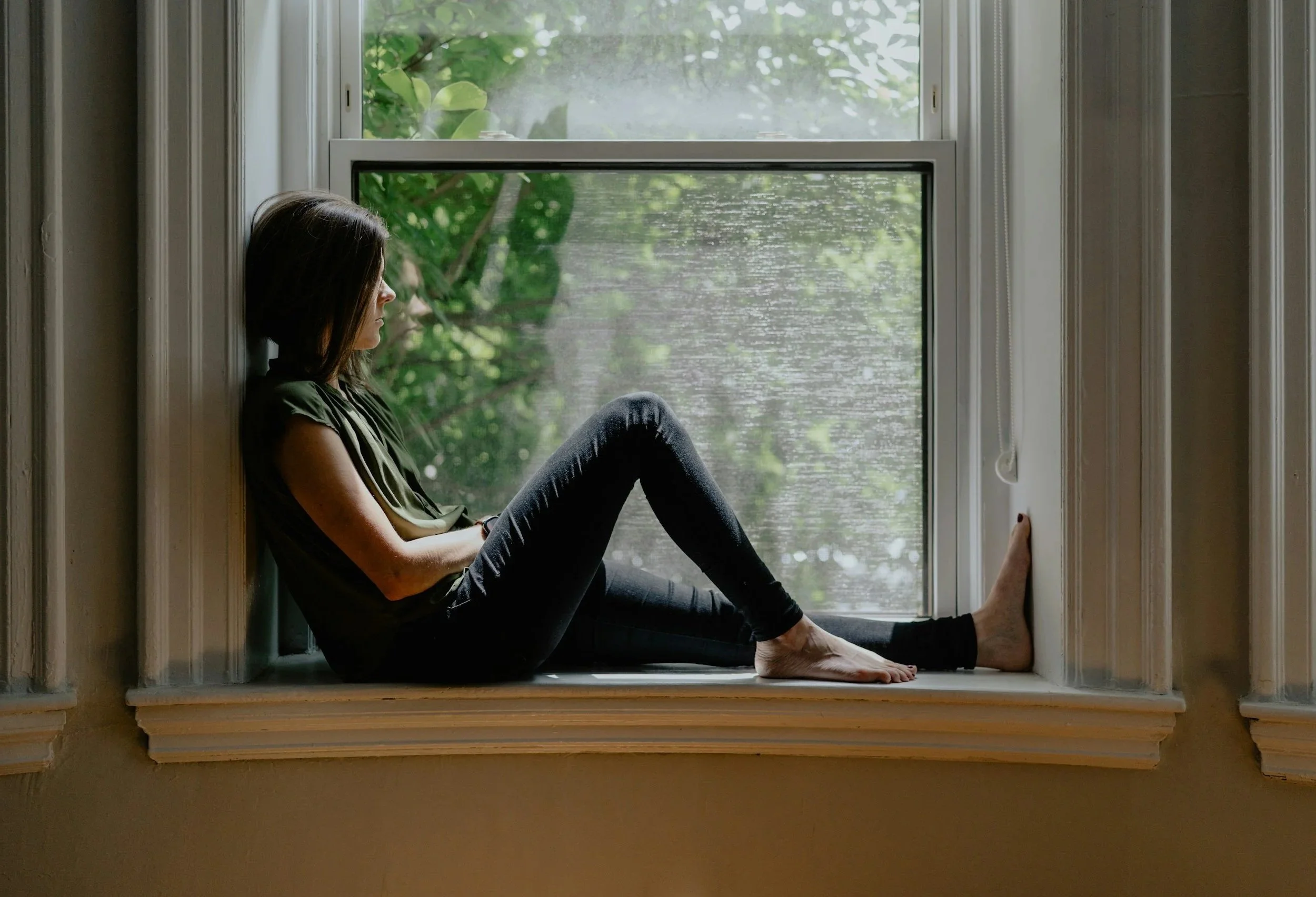 Thoughtful woman sitting by a window in soft natural light