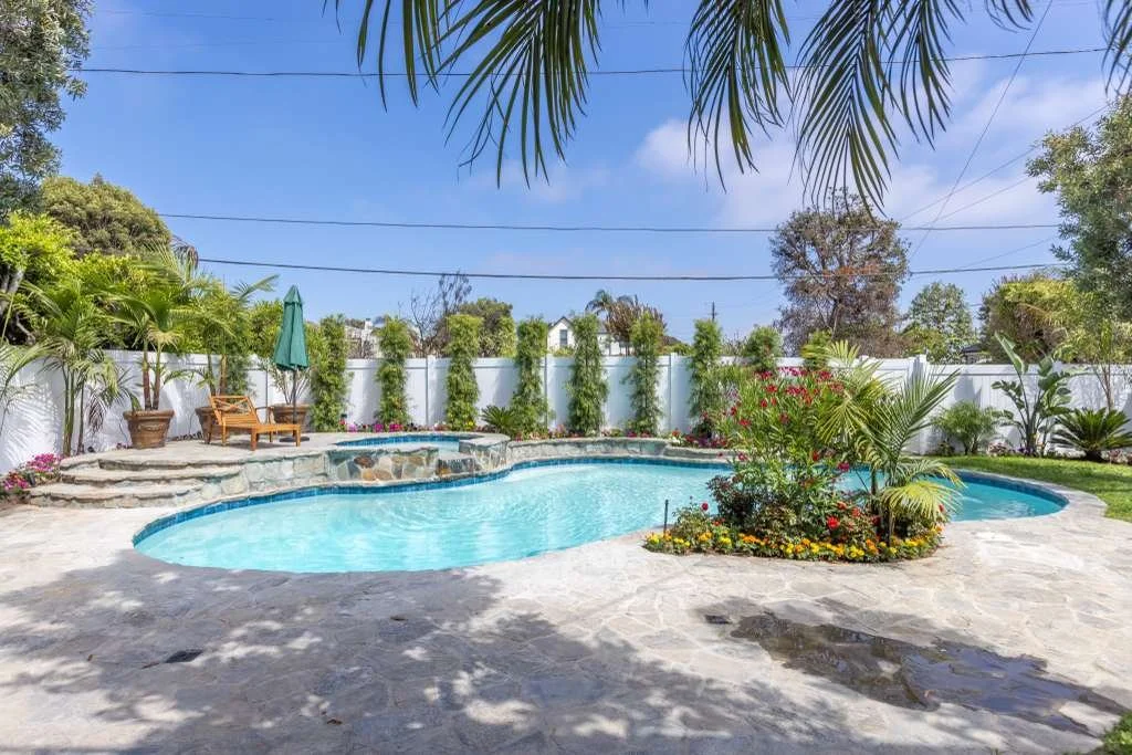 Fully restored backyard with pool, landscaping, and privacy wall after fire damage reconstruction