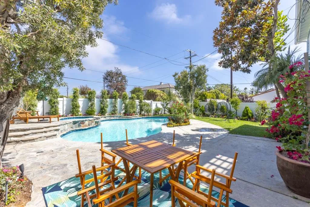 Restored backyard with pool, patio seating, and landscaped garden after fire damage