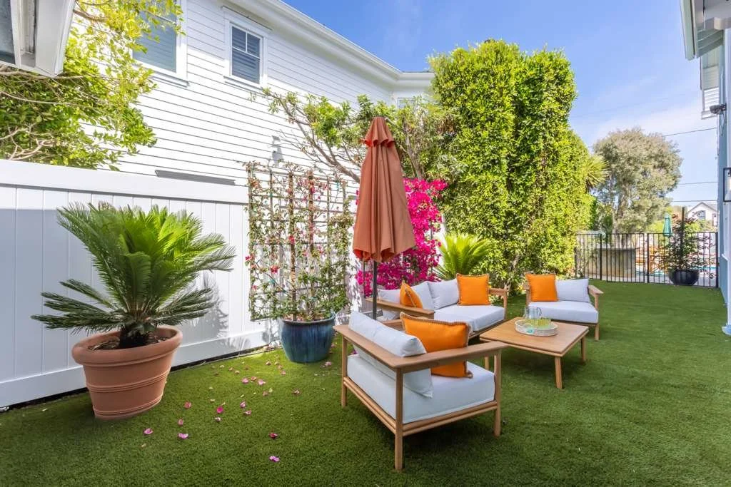 Backyard seating area with outdoor furniture, grass, and landscaping after reconstruction