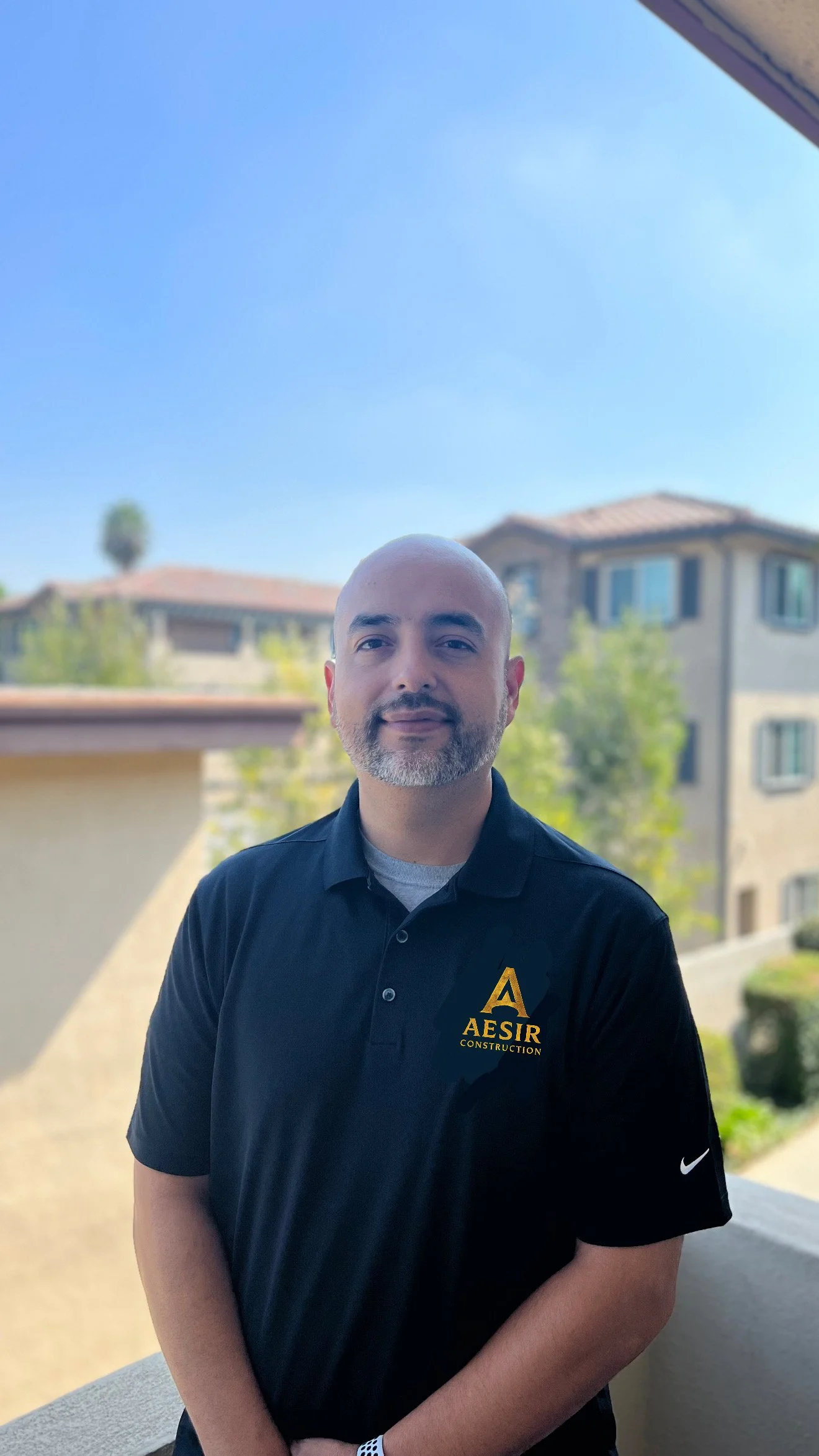 Owner of Aesirco Construction standing outdoors in company-branded shirt
