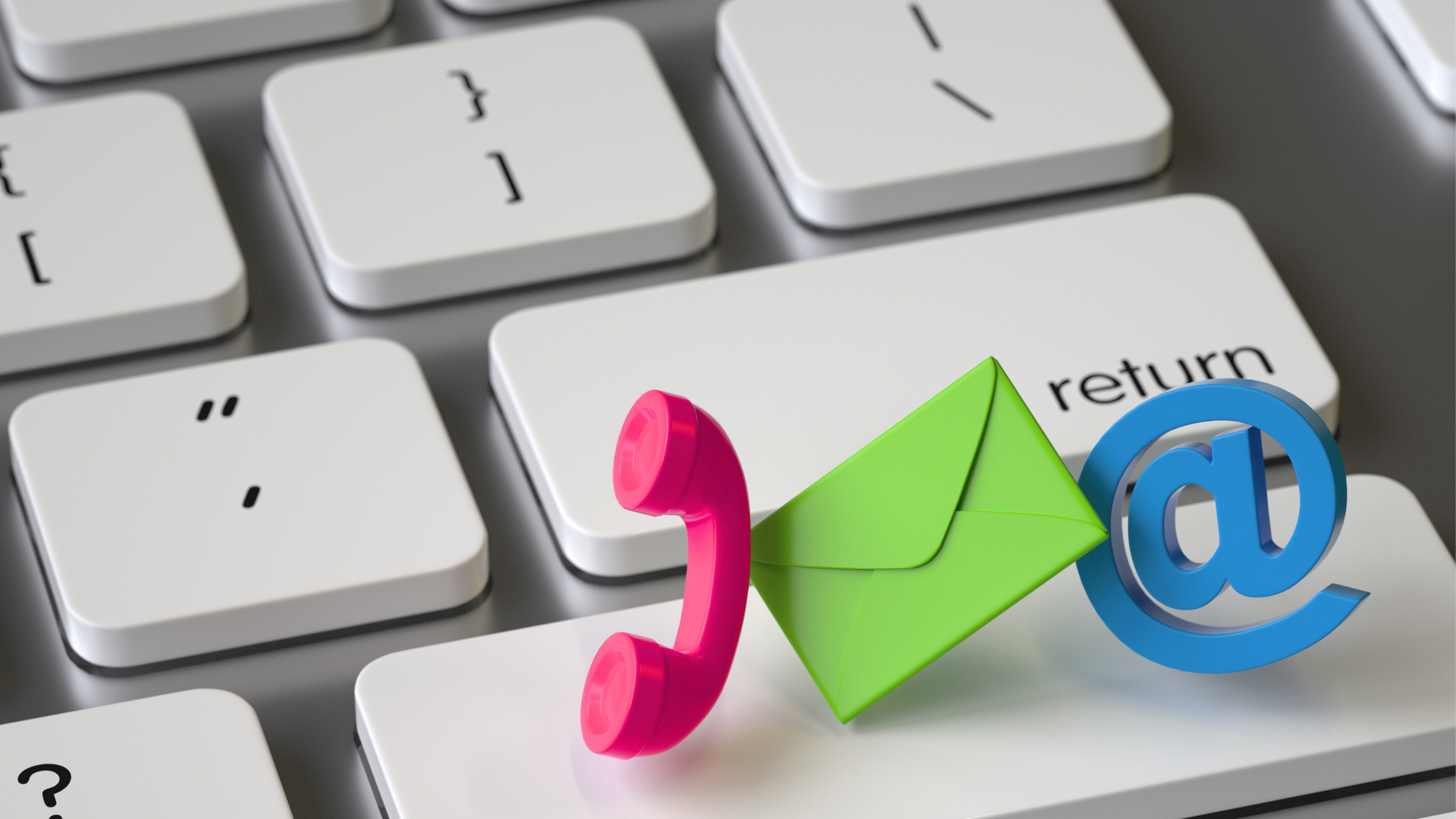 A computer keyboard with a green email icon, a pink phone receiver, and a blue at symbol (@) placed on the return key.