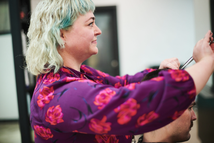 A woman with pastel green and blonde hair getting her hair styled by a hairstylist.