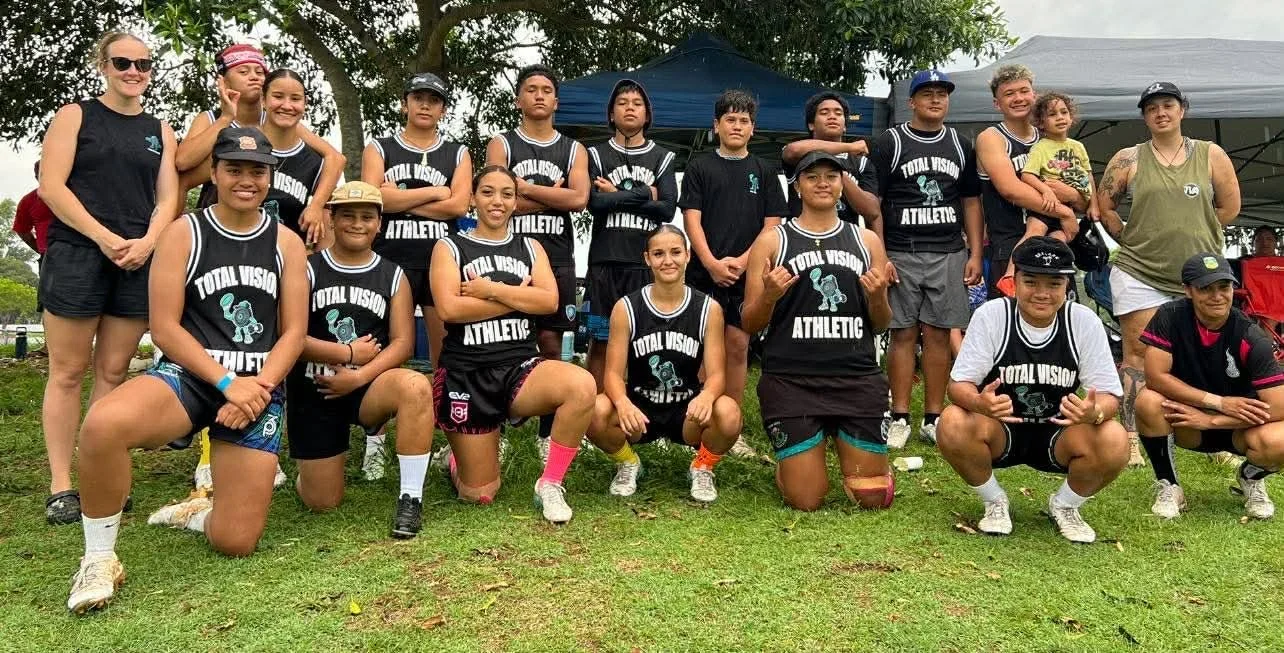 Group of young athletes, mostly girls, wearing black sports uniforms with
