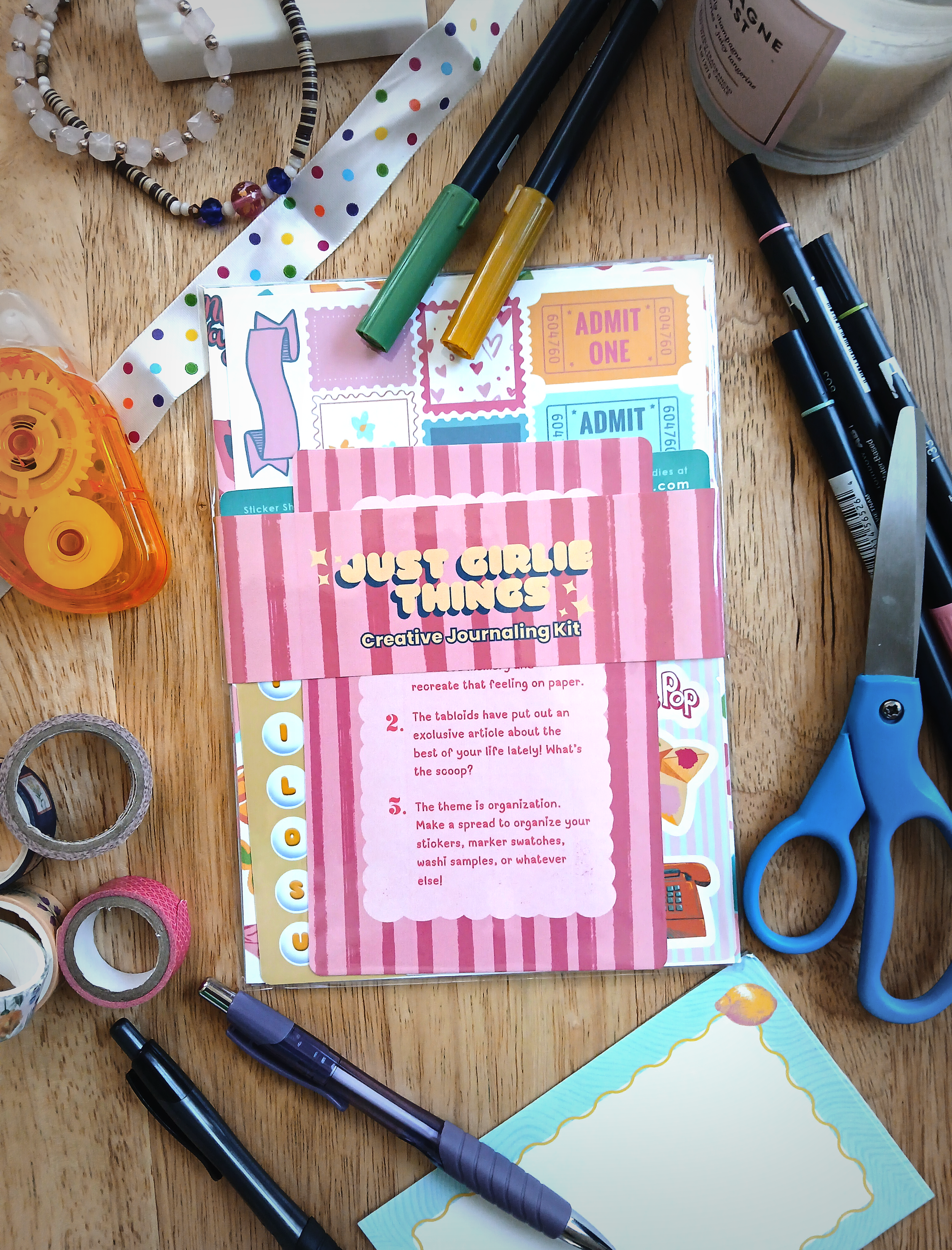 a table covered in junk journal supplies with the "Just Girlie Things Junk Journaling Kit" in the middle