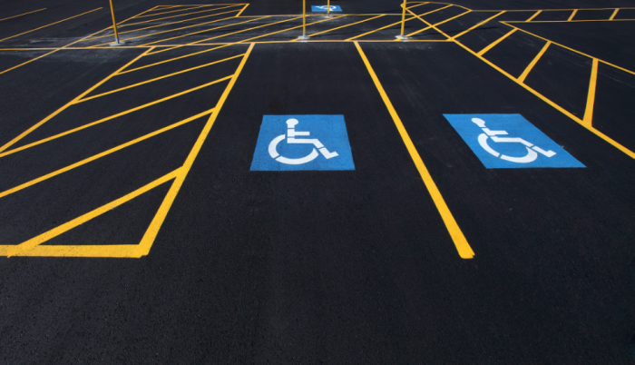 Parking lot with two designated accessible parking spaces marked with blue wheelchair symbols and yellow lines.